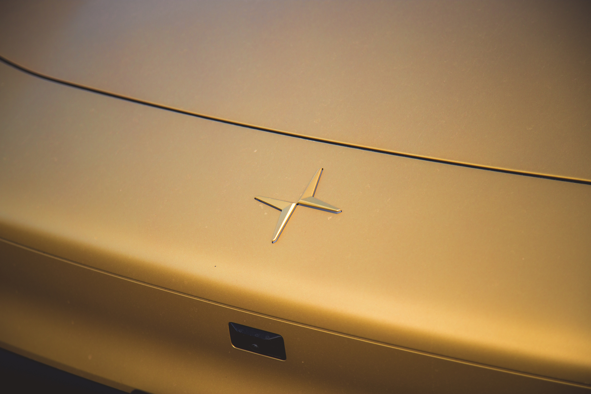 Primer plano de la superficie de un automóvil dorado con un logotipo plateado con un diseño de 