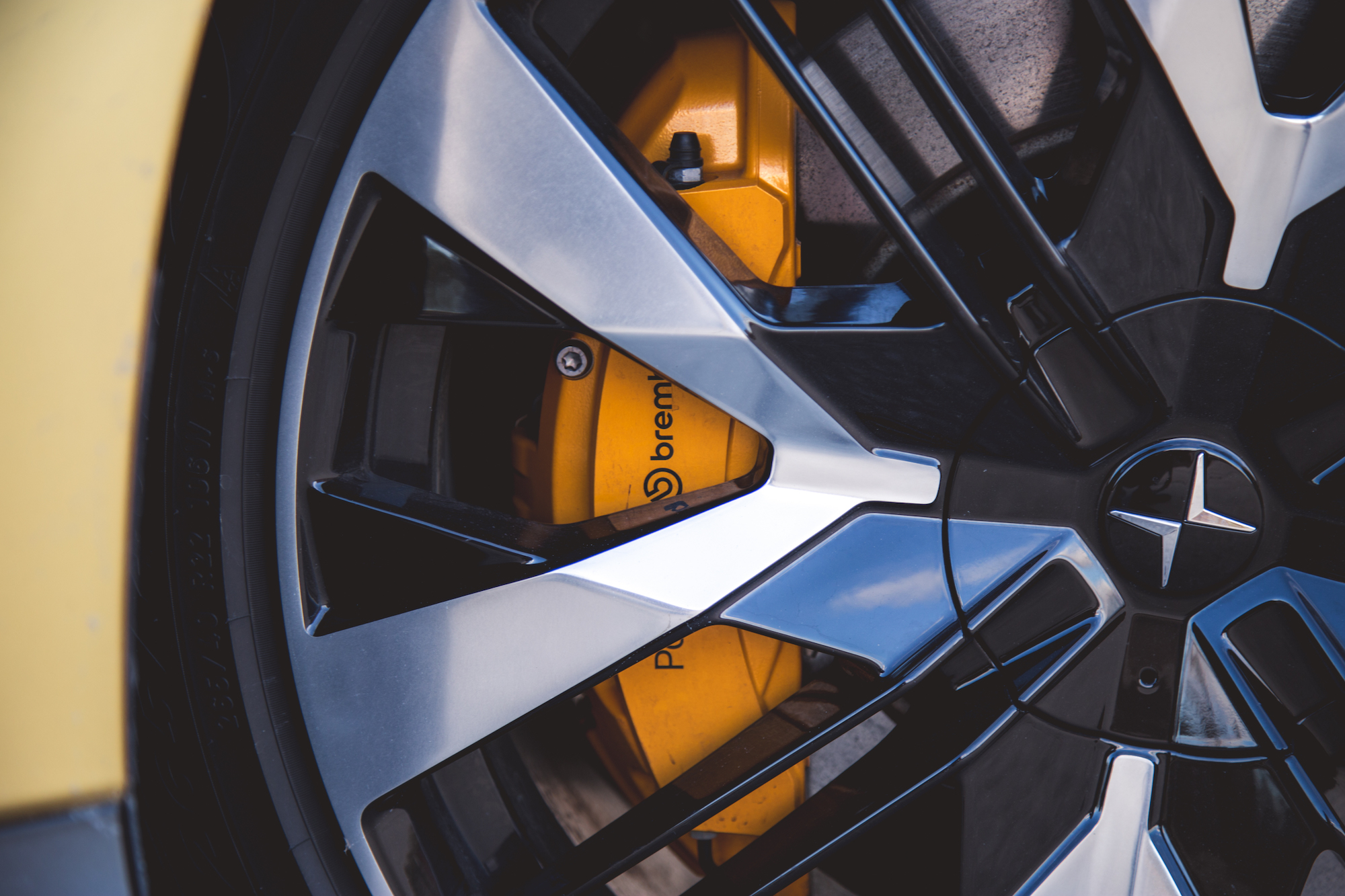 Primer plano de una rueda de automóvil que muestra una llanta de aleación negra y plateada con una pinza de freno amarilla visible.