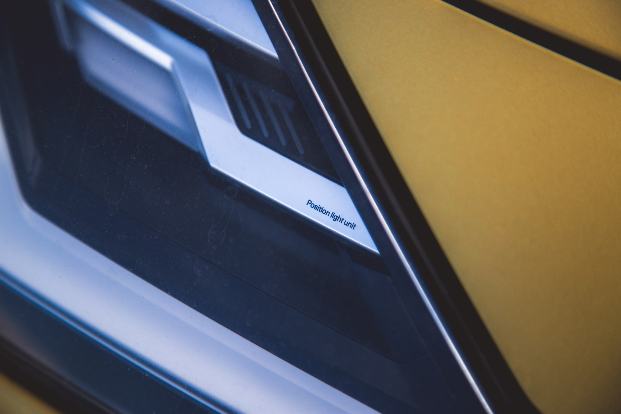 Primer plano de la unidad de luz de posición de un automóvil sobre una superficie metálica.