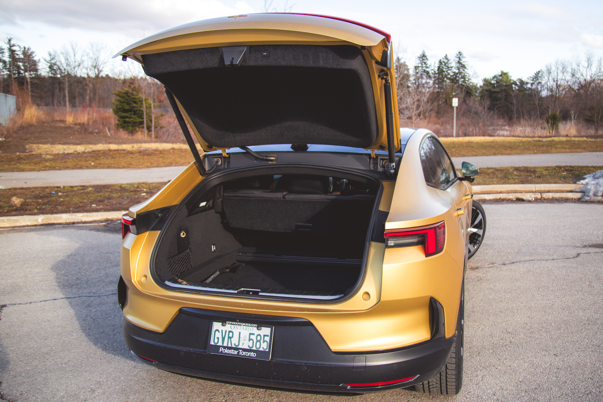 Vista trasera de un vehículo eléctrico dorado con maletero abierto, que muestra una amplia zona de carga.