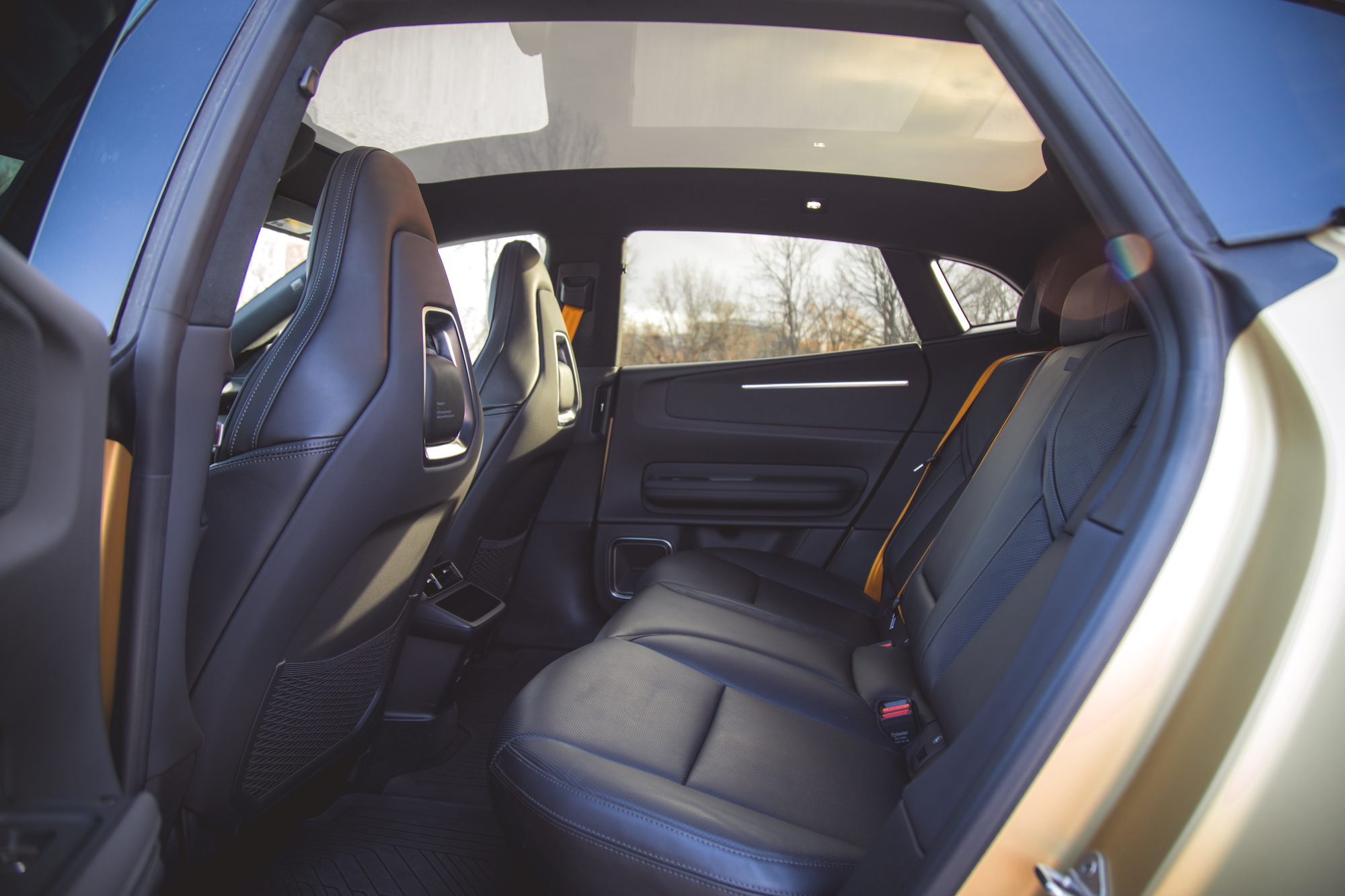 Vista interior del asiento trasero de un automóvil con dos asientos de cuero negro y un gran techo corredizo.