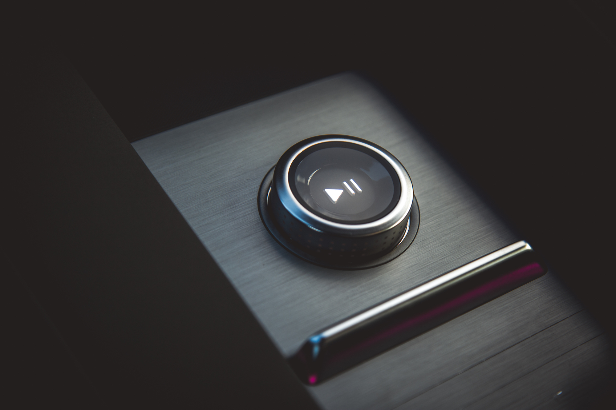 Primer plano de un botón de reproducción de metal sobre una superficie elegante.