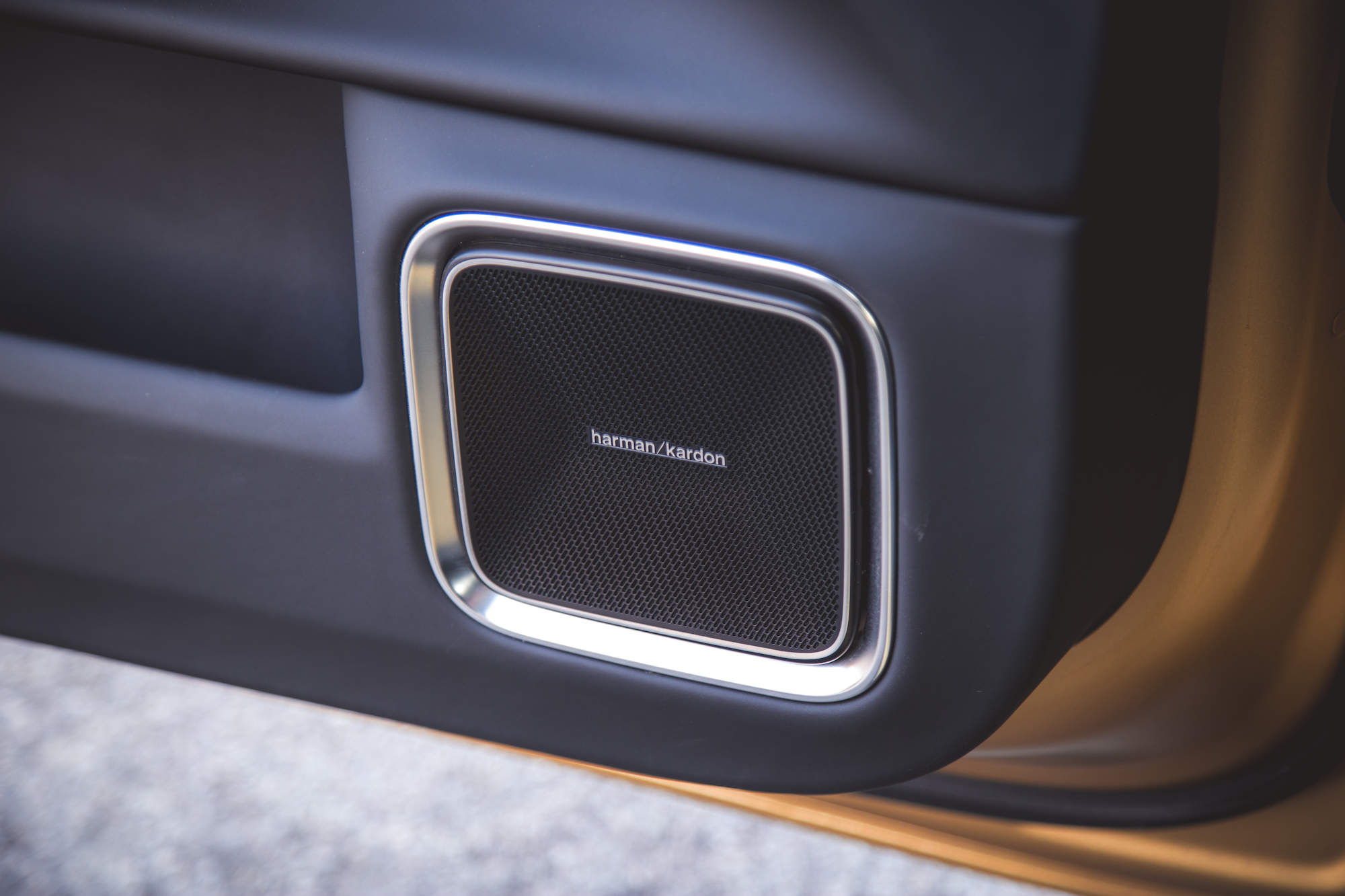 Primer plano de un altavoz Harman Kardon montado en el interior de la puerta de un automóvil.