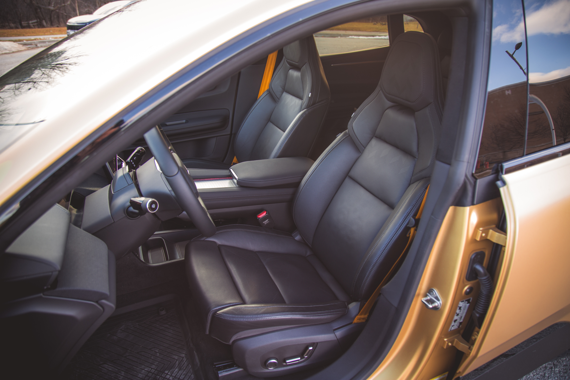 Vista interior de un automóvil que muestra asientos de cuero negro, un volante y una consola central.