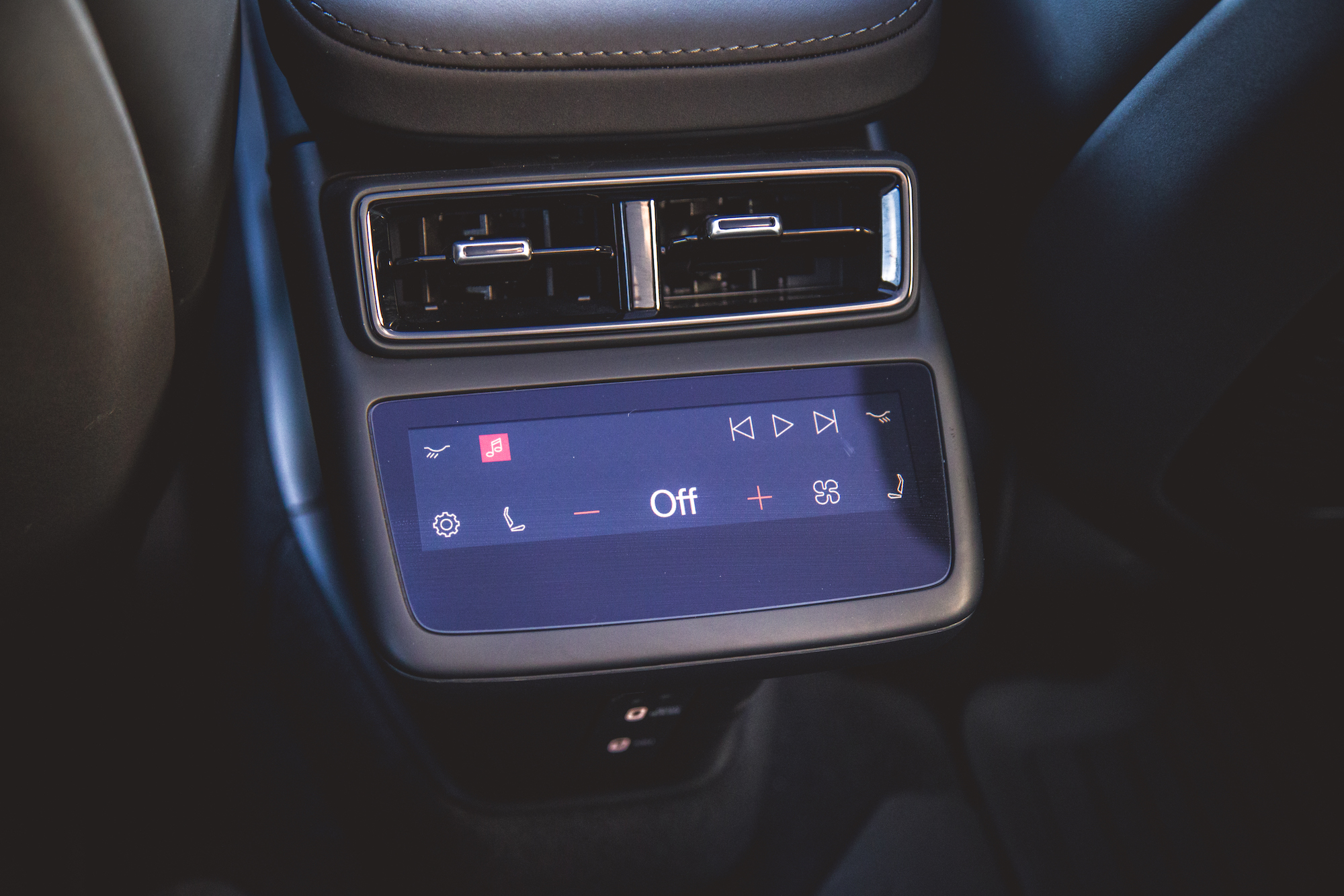 Primer plano del panel de control de un automóvil moderno que muestra la configuración de clima y audio, con una pantalla que indica 