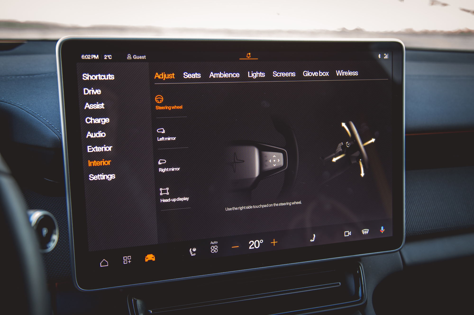 Pantalla interior que muestra configuraciones para el ajuste del volante, espejos, head-up display y funciones de control de clima en un automóvil.