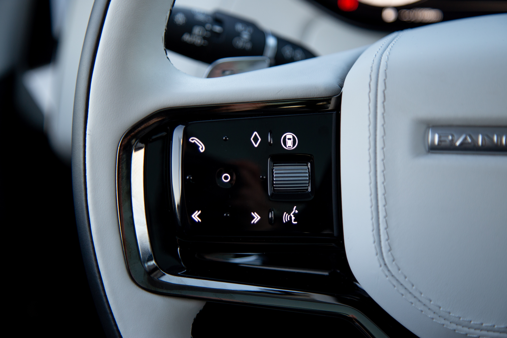 Close-up of a modern car steering wheel control panel featuring various buttons for phone, navigation, and settings.