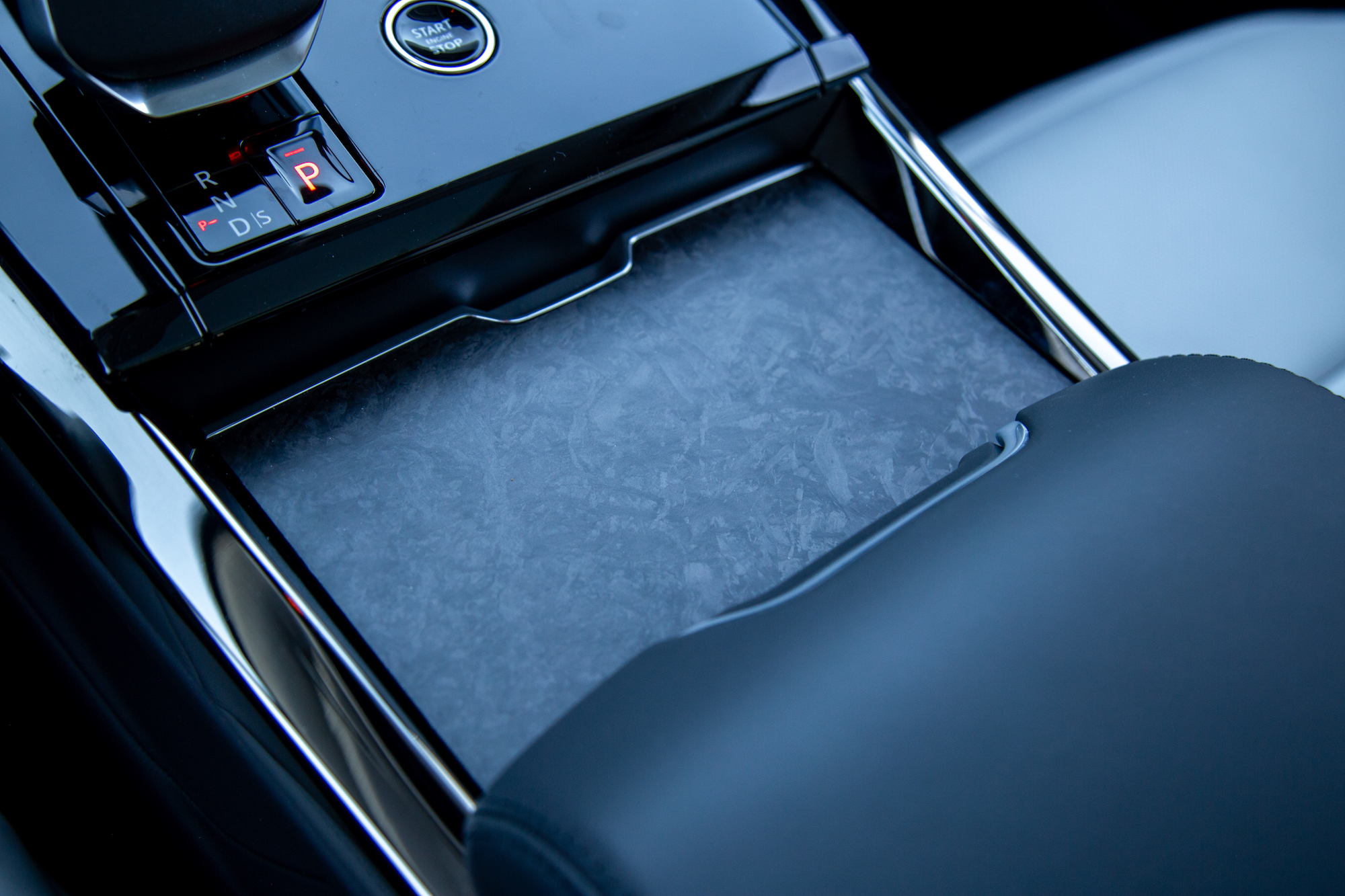 Close-up of a car's center console featuring gear shift buttons and a sleek storage compartment.
