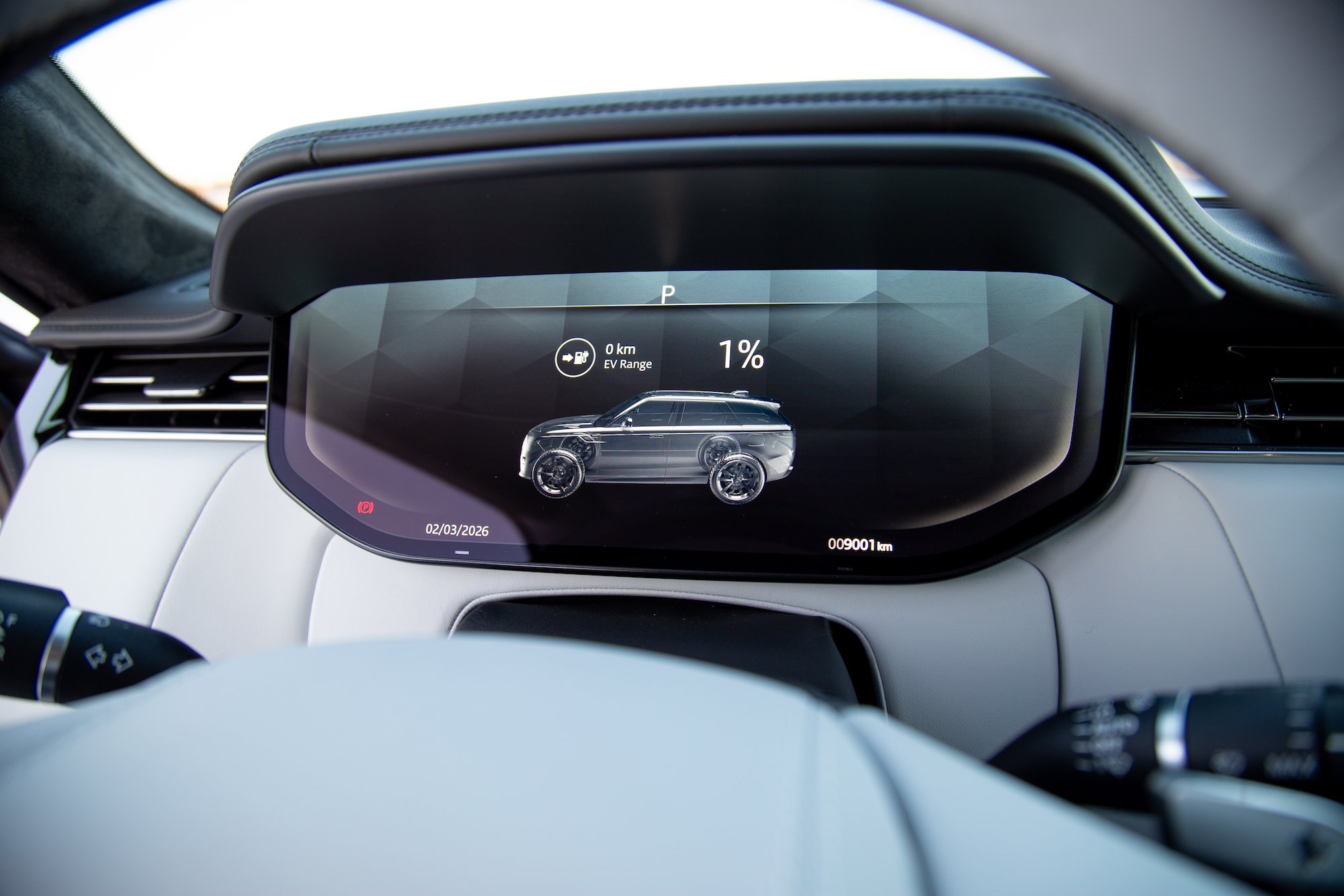 Close-up view of a car's digital dashboard displaying '1% EV Range' and '0 km', with a graphic of an SUV on the screen.