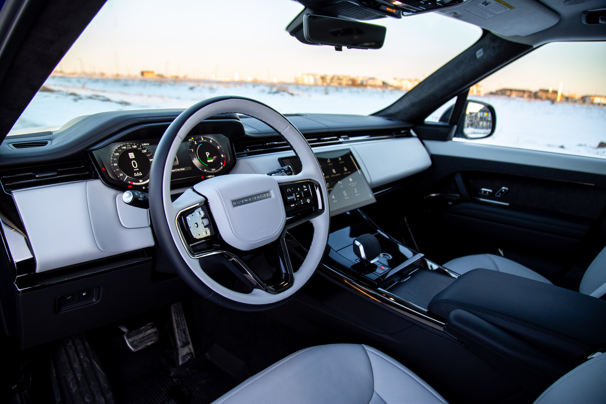 Interior view of a modern car showcasing the steering wheel, dashboard with digital displays, and a touchscreen interface, highlighted by a sleek design and luxury finishes.