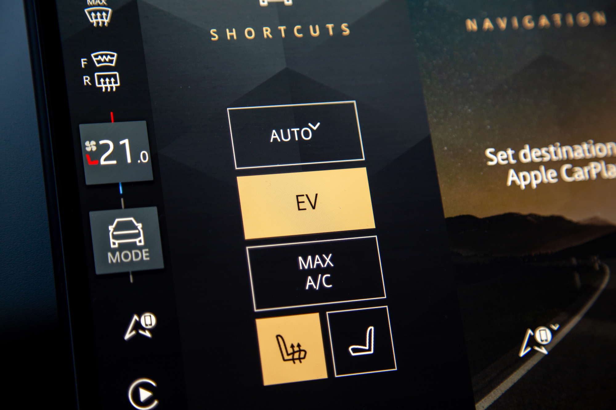 Close-up of a digital dashboard display showing climate control options including 'AUTO', 'EV', and 'MAX A/C', with a current temperature setting of 21.0 degrees Celsius.