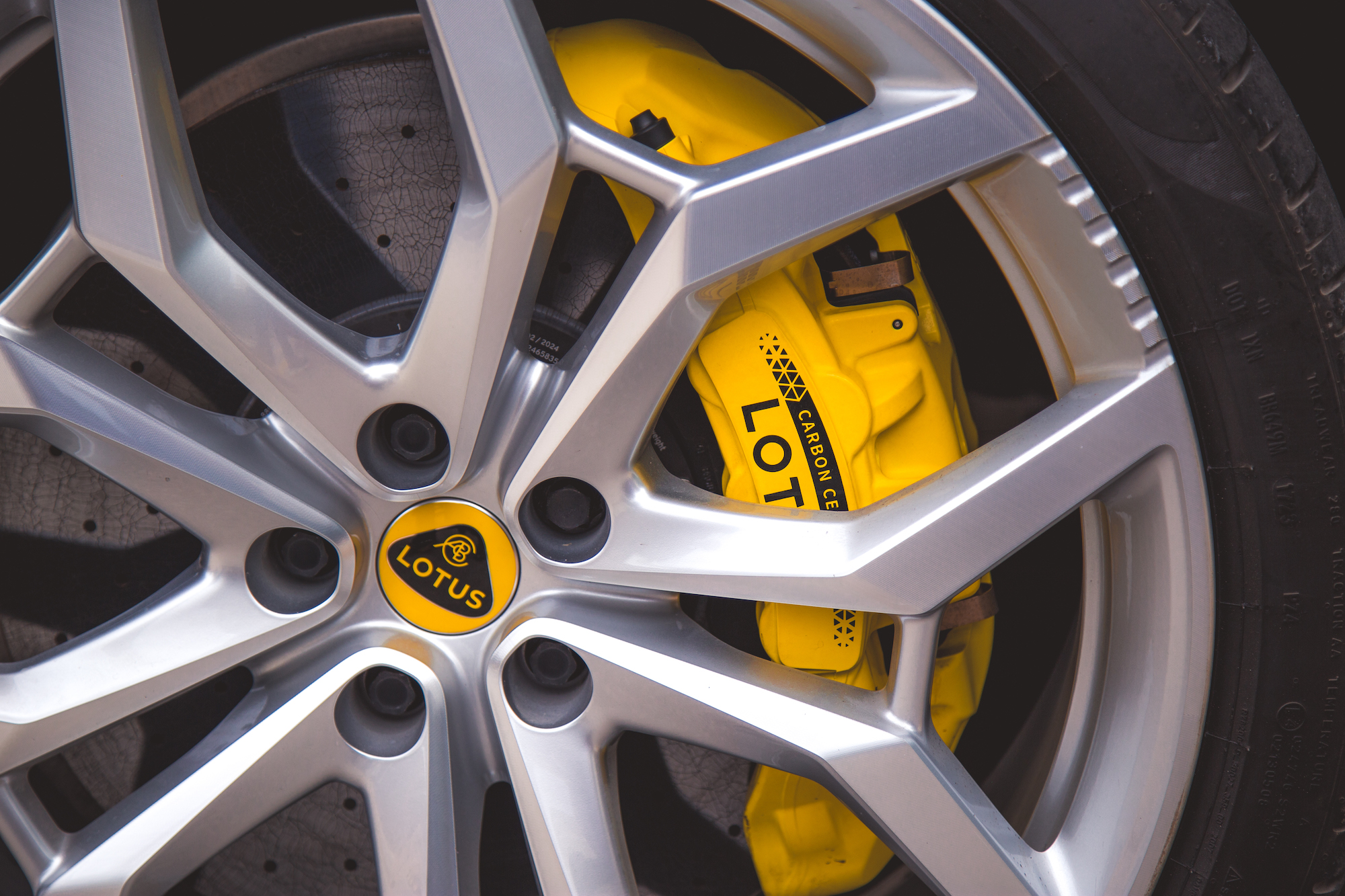 Primer plano de una llanta de aleación plateada con una pinza de freno Lotus amarilla y un neumático negro.