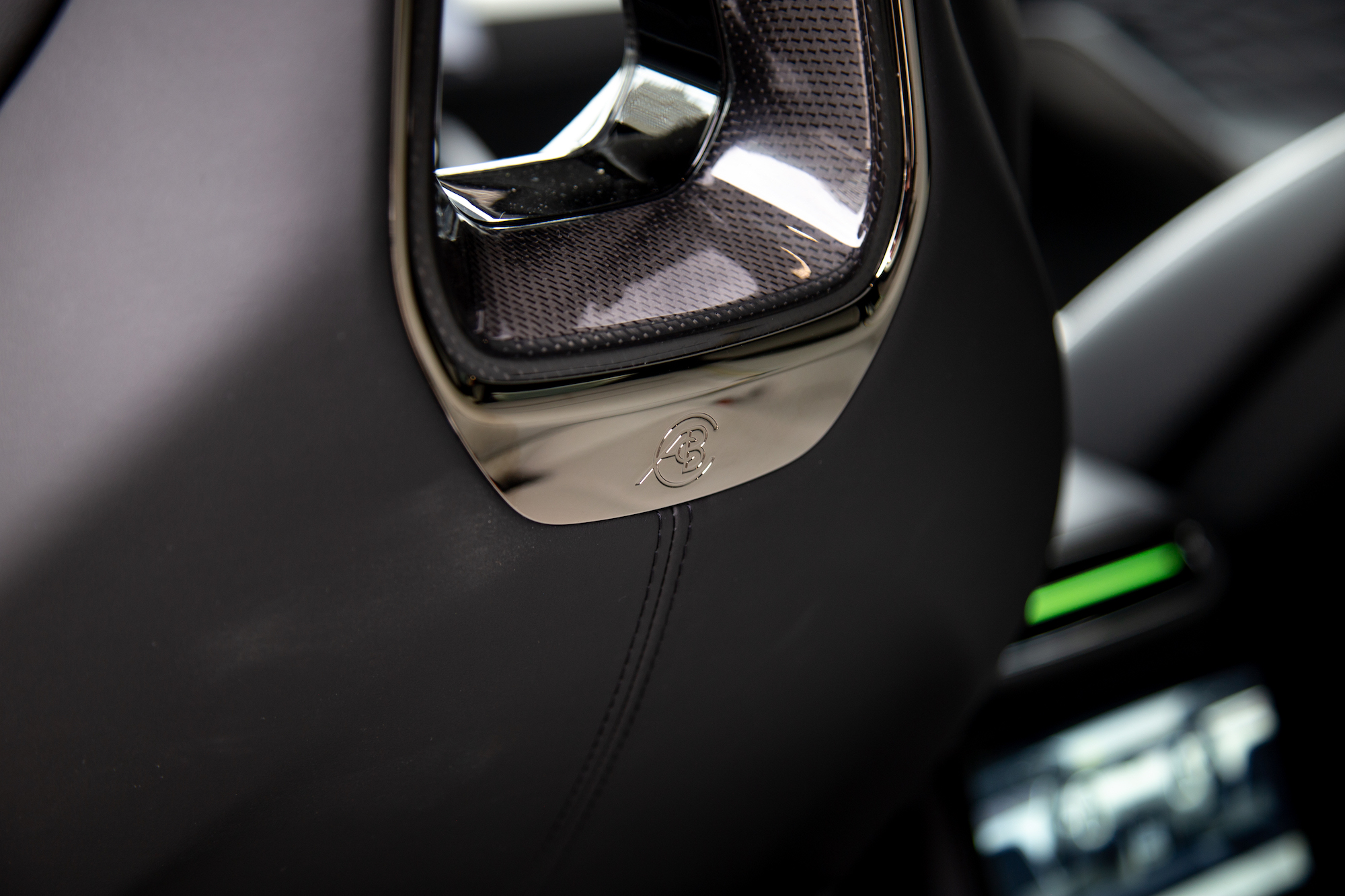 Primer plano del reposacabezas de un asiento de automóvil con un detalle de emblema cromado y una superficie texturizada.