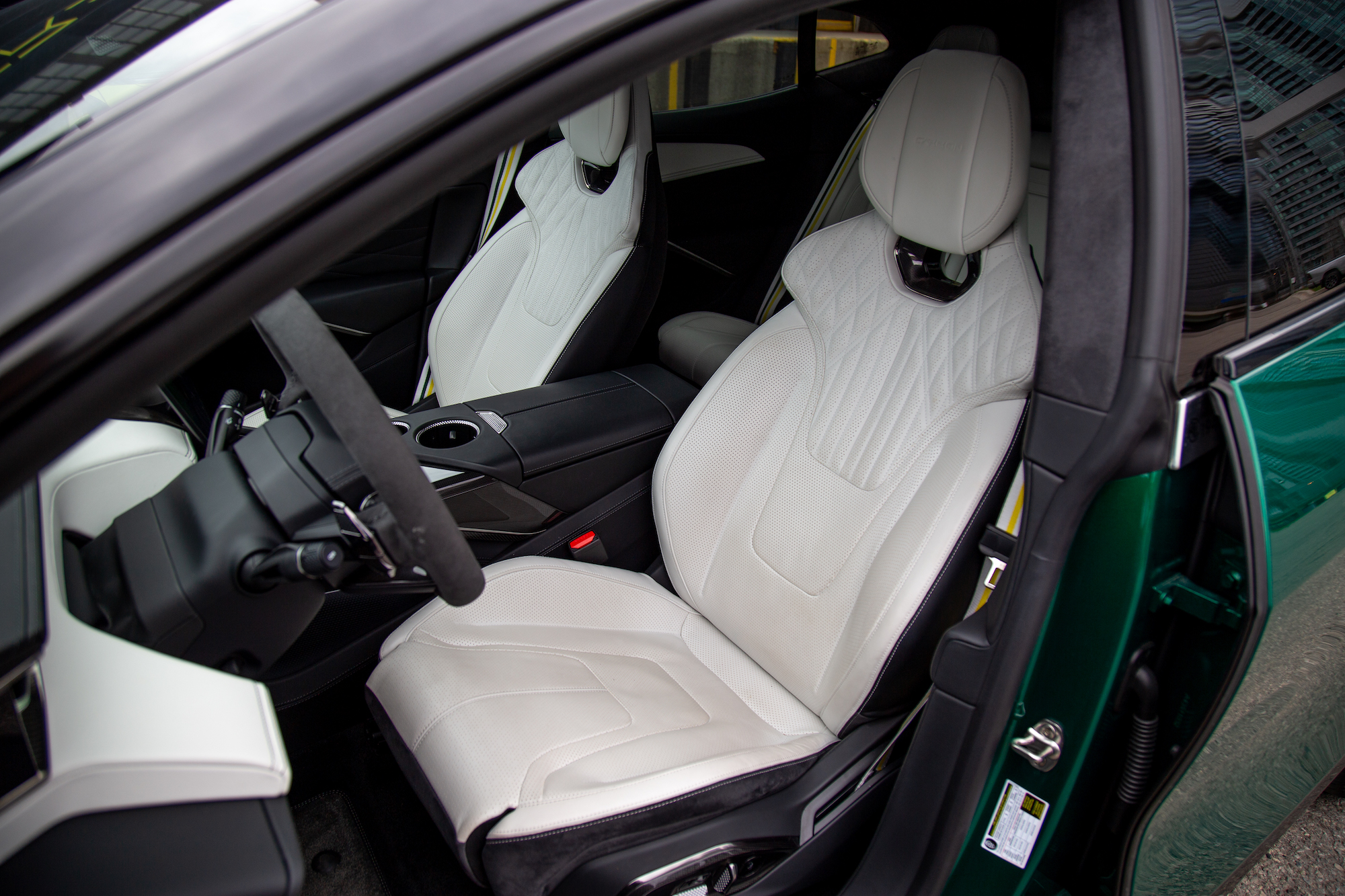 Vista interior de un automóvil que exhibe modernos asientos de cuero blanco con costuras intrincadas y un elegante volante.