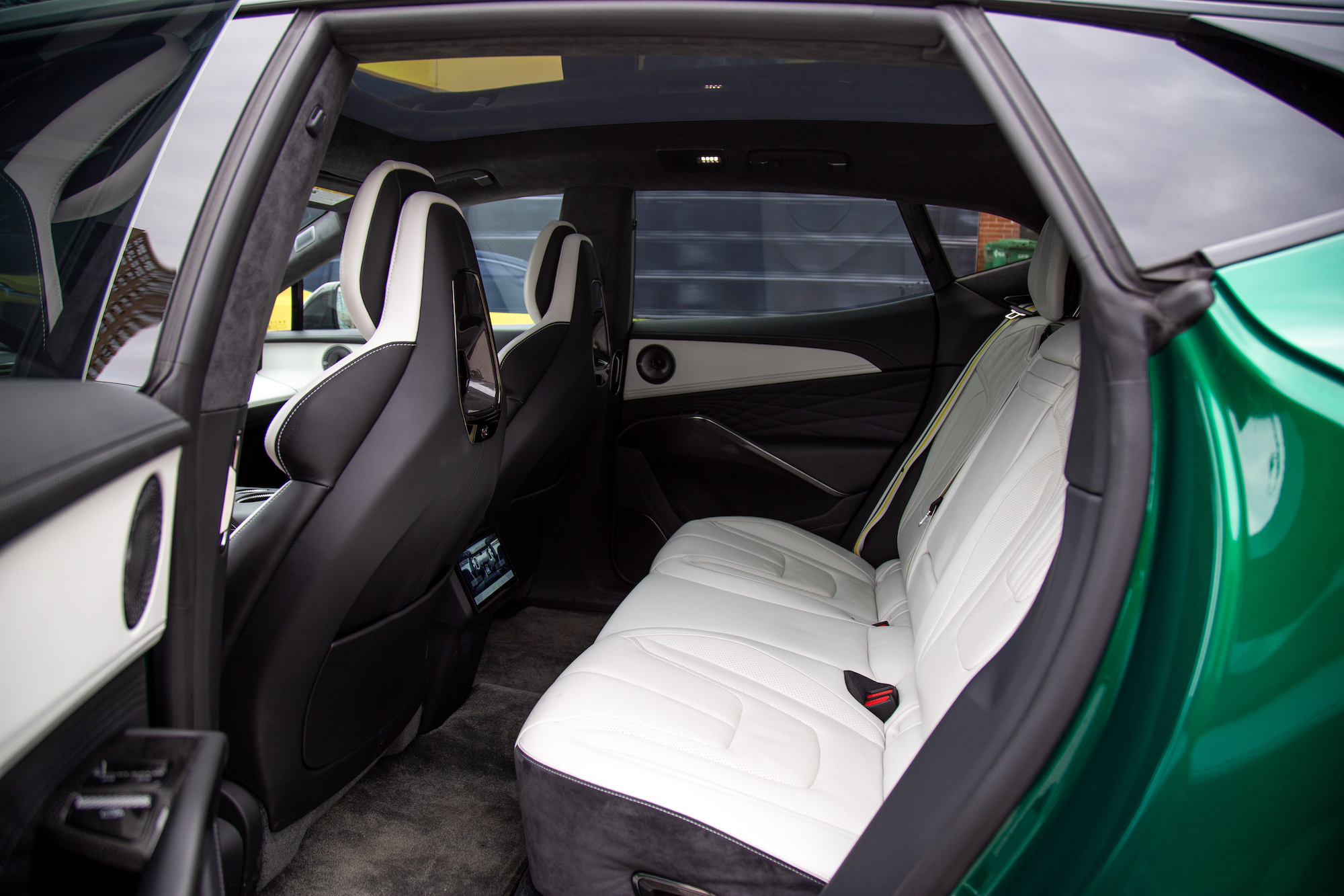 Vista interior de un automóvil de lujo que muestra el asiento trasero con tapicería de cuero blanco y negro y elementos de diseño moderno.