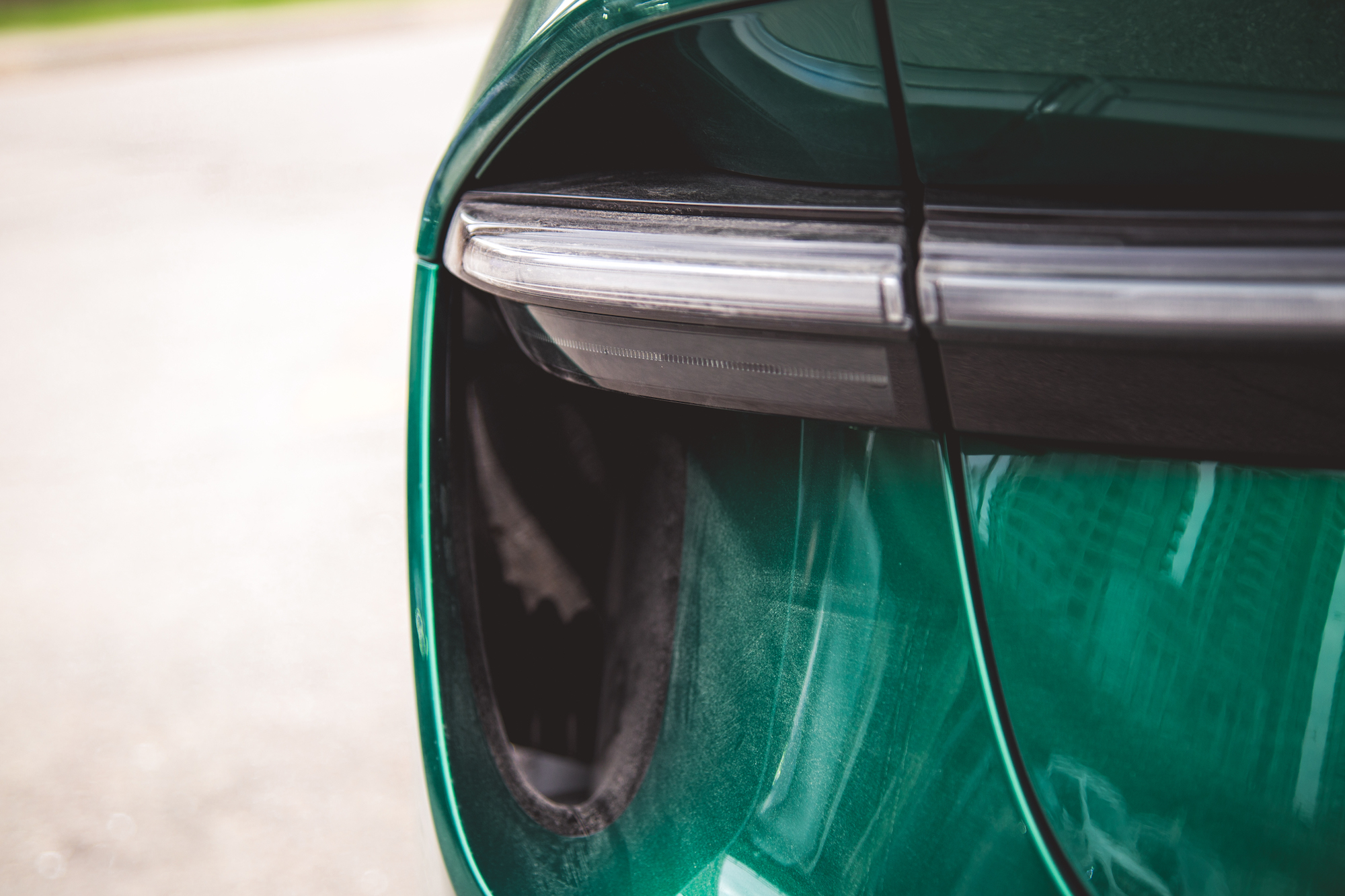 Primer plano de la luz trasera y la carrocería de un automóvil verde, que muestra el diseño elegante y el acabado suave.