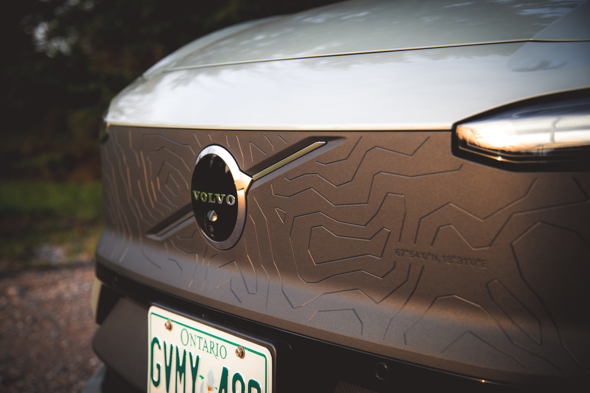 Primer plano de la parte trasera de un automóvil Volvo con intrincados patrones geométricos en la superficie y el emblema en un lugar destacado.