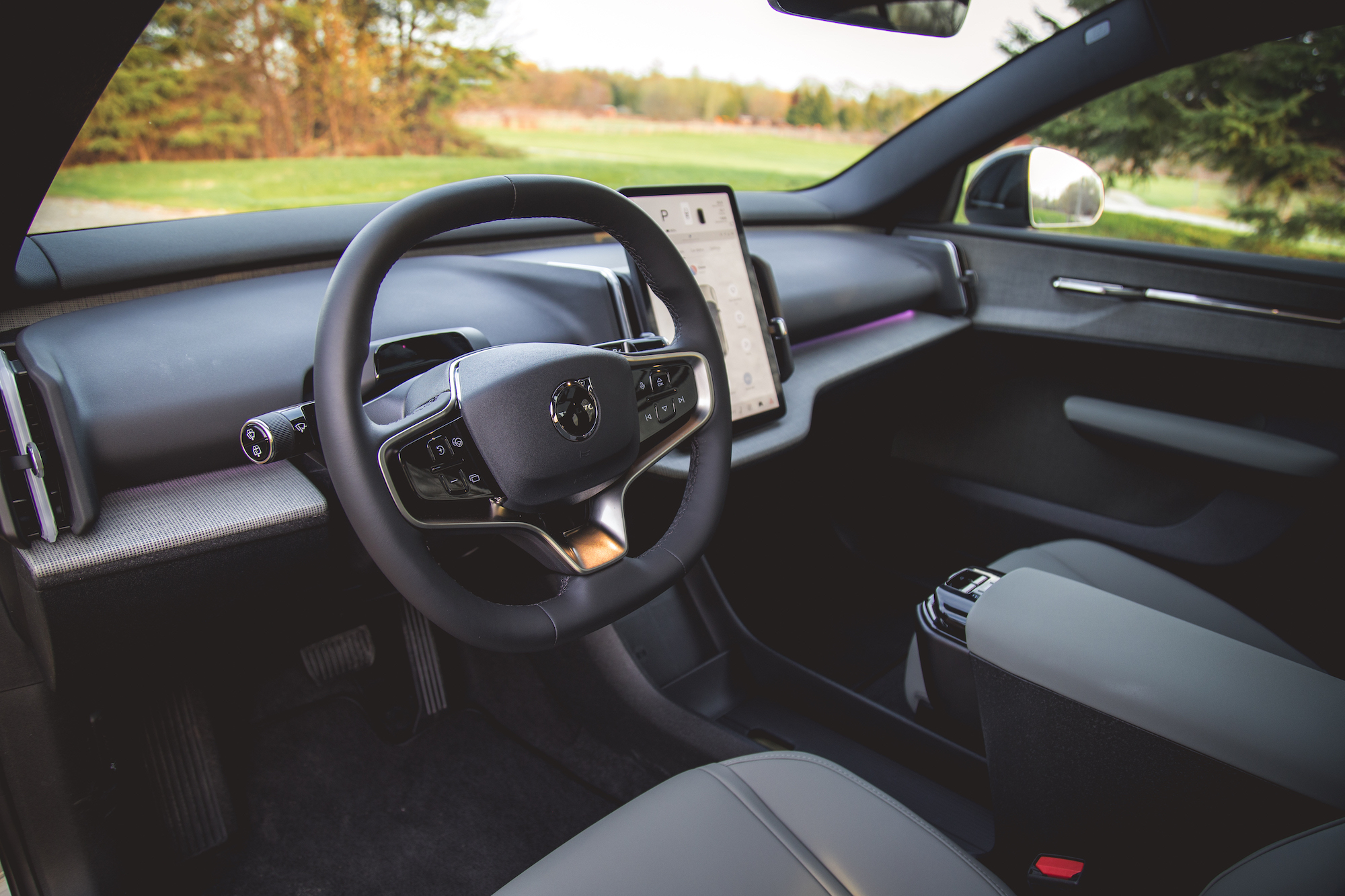 Vista interior de un automóvil moderno que muestra el volante, el tablero con pantalla táctil y la consola central.