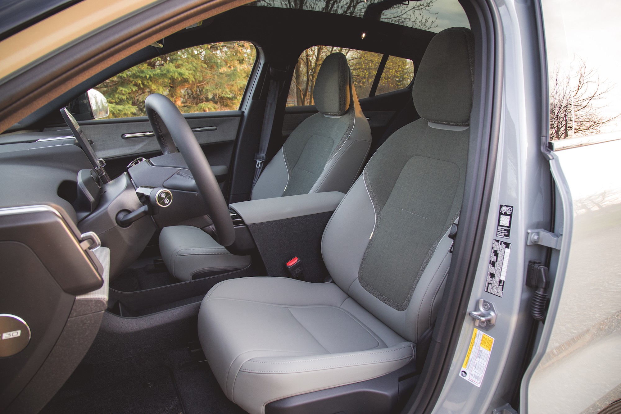Vista interior de un automóvil moderno que muestra dos asientos delanteros, un volante y un tablero con pantalla táctil.
