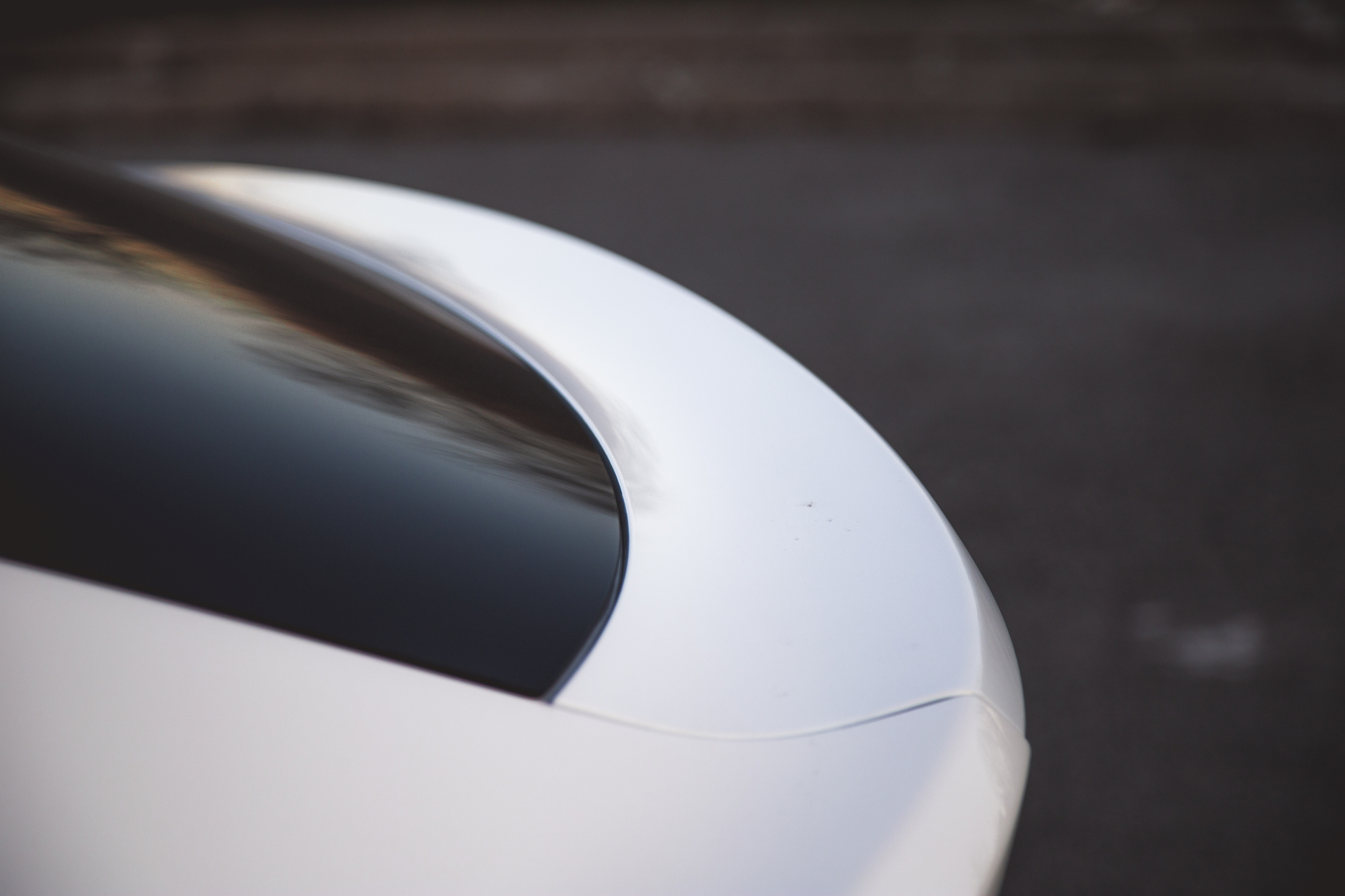 Close-up of the rear edge of a white car, showcasing its sleek design and glossy finish.