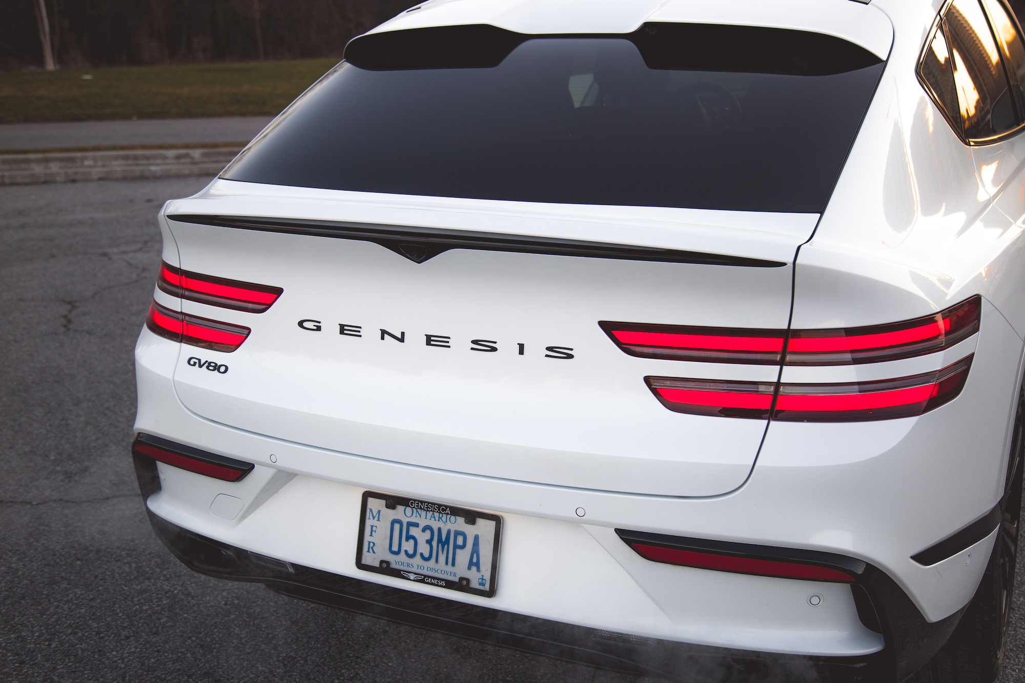 Rear view of a white Genesis GV80 SUV showcasing its sleek design and distinctive taillights.