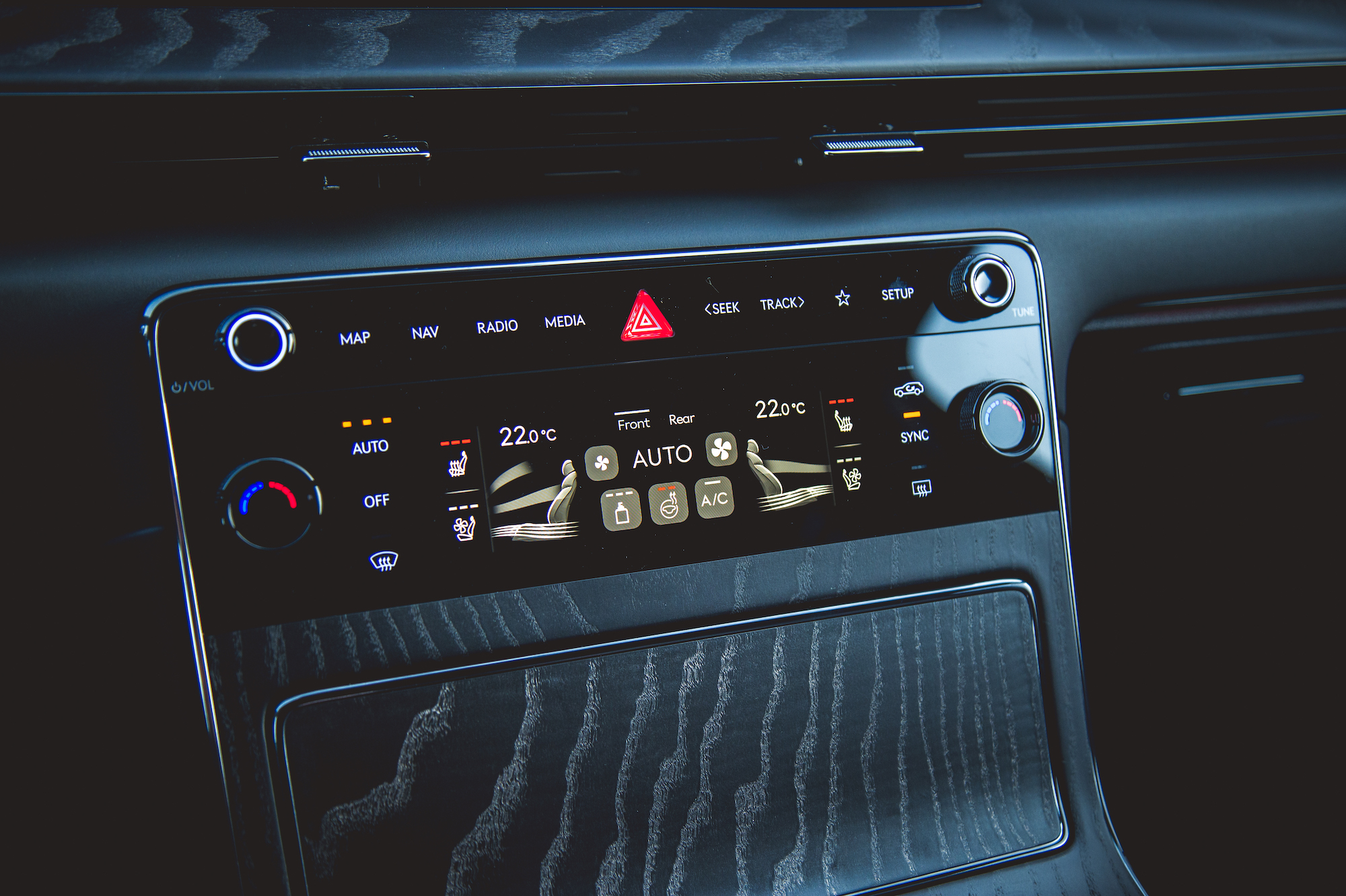 Close-up view of a car's climate control panel featuring temperature settings, fan controls, and media buttons.