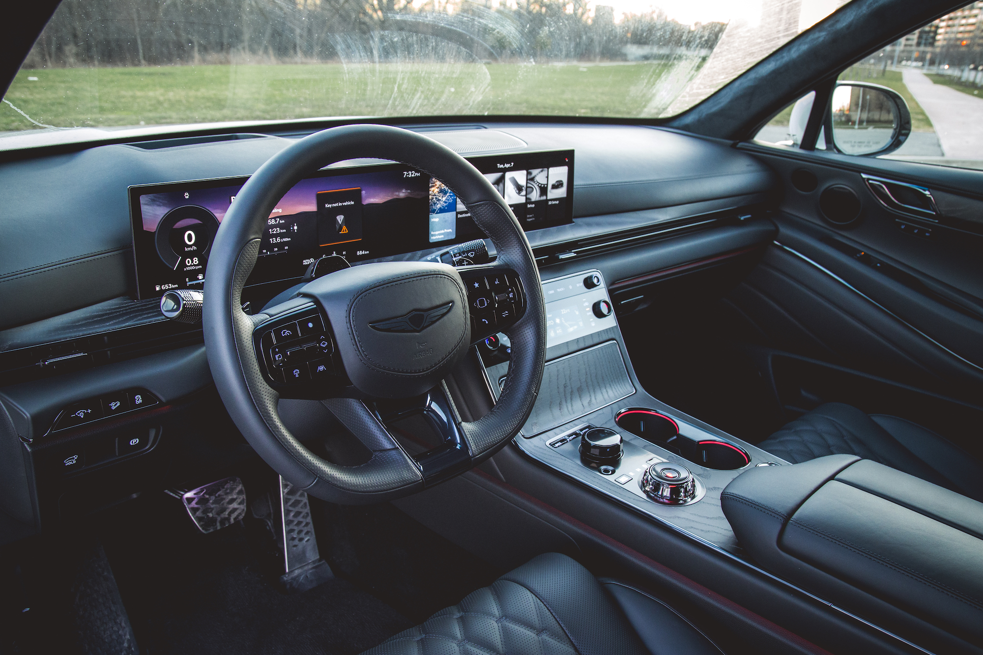 A view of the interior of a modern car, featuring a steering wheel with controls, a dashboard display showing various driving metrics, and a sleek center console with an infotainment system.