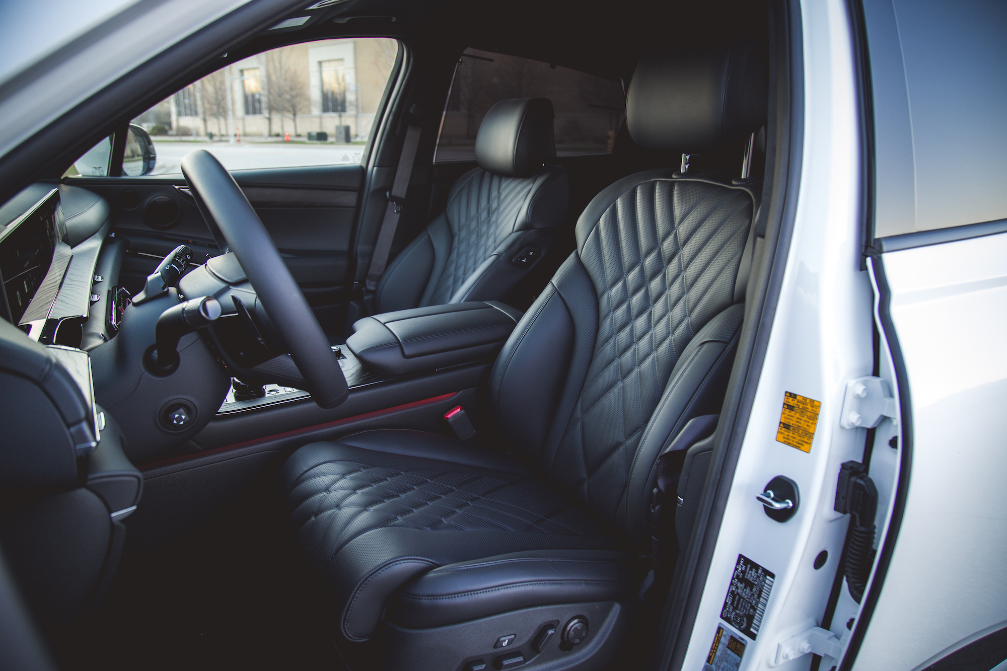 Interior view of a luxury vehicle showcasing black leather seats with diamond stitch patterns and modern dashboard controls.
