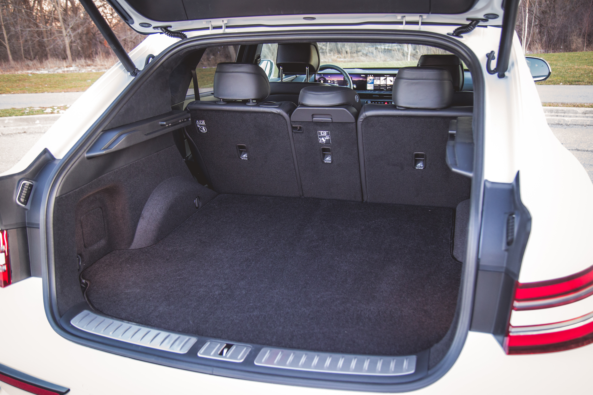 Interior view of a car's trunk space, showcasing a clean, spacious area with black carpet and rear seats in an upright position.