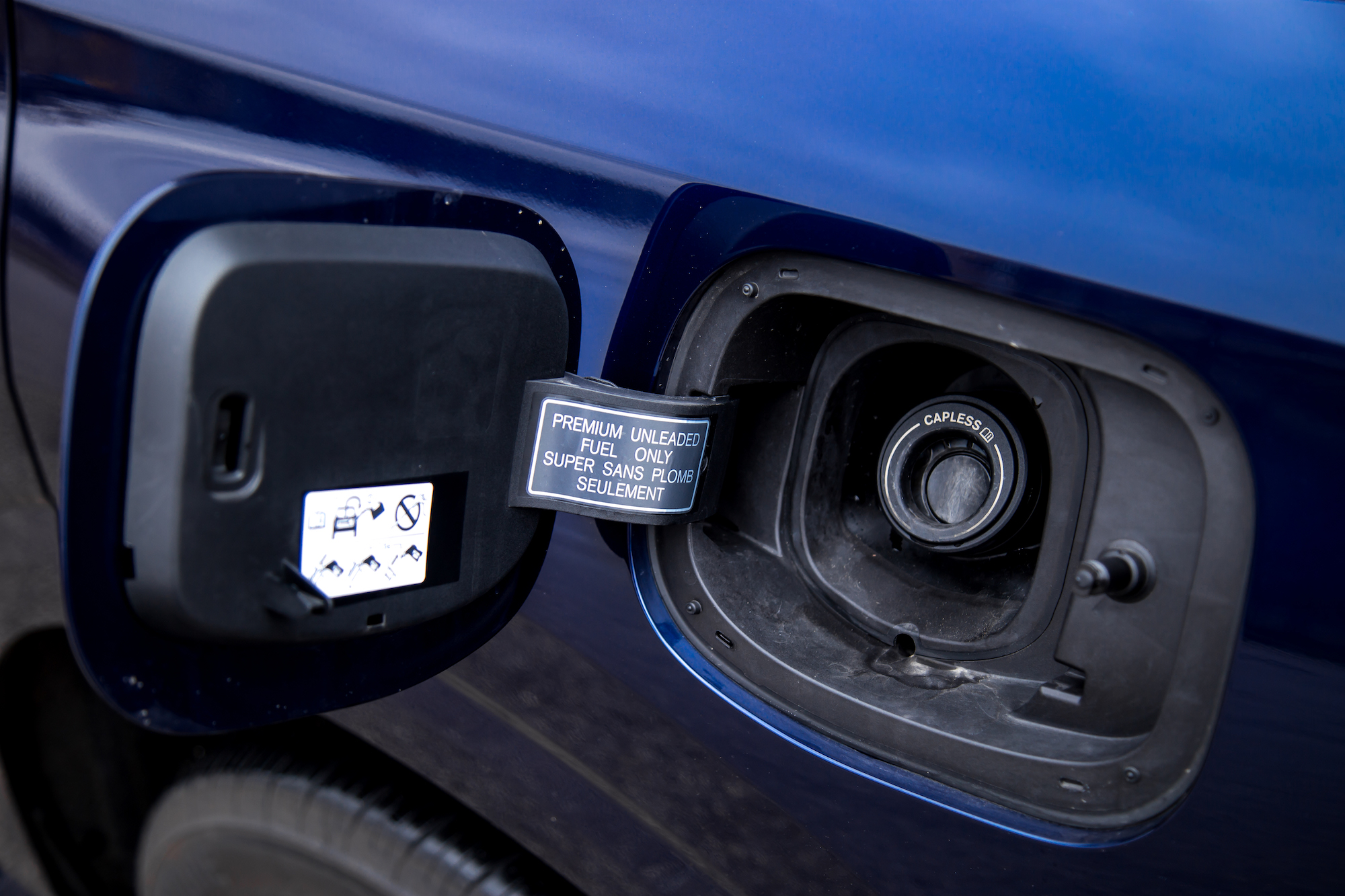 Primer plano de una tapa de combustible en un vehículo azul, que muestra una etiqueta que dice 
