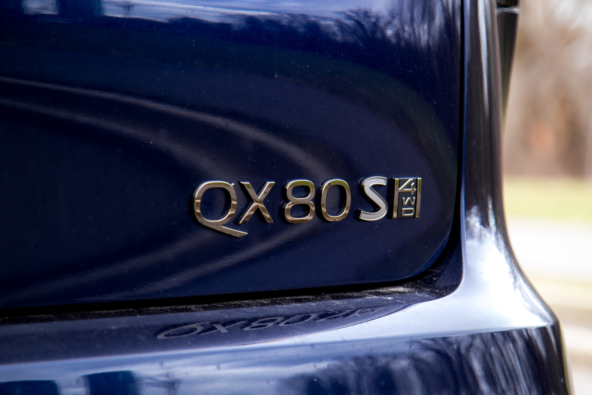 Primer plano de la insignia QX80 S 4WD en un vehículo azul