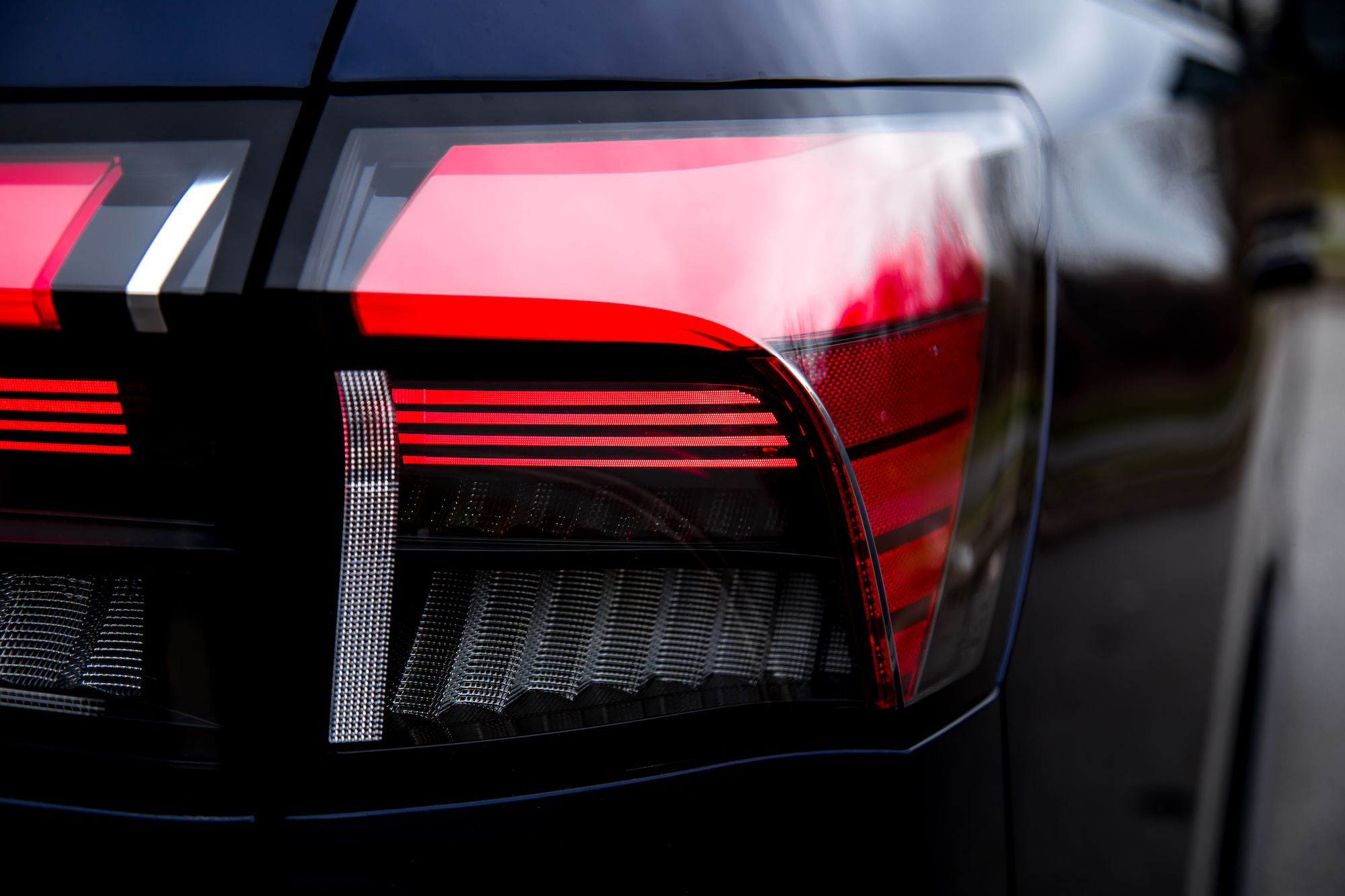 Primer plano de la luz trasera de un automóvil moderno que muestra elementos luminosos rojos y blancos.