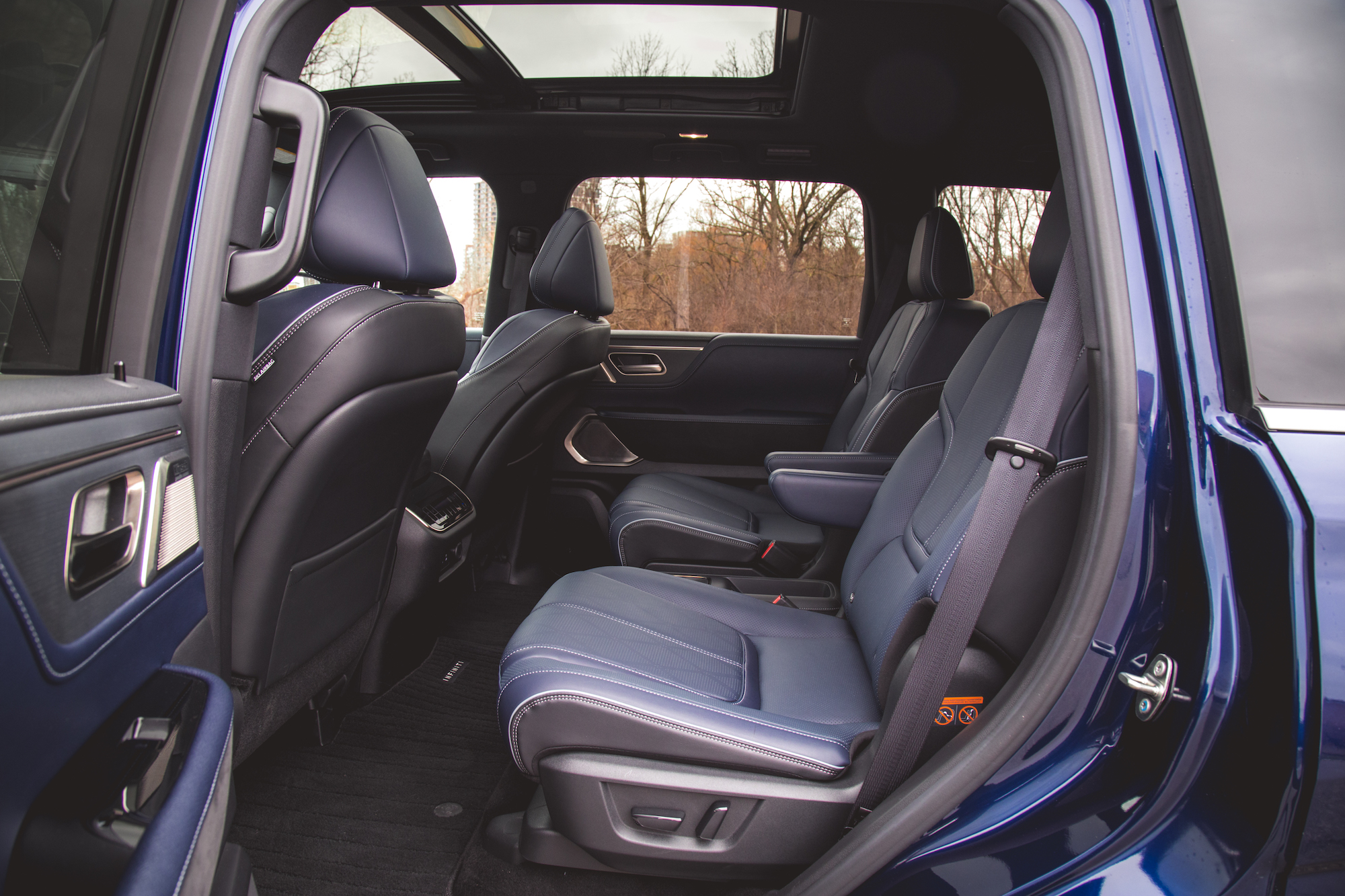 Vista interior de un asiento trasero espacioso con dos cómodos asientos de cuero y un techo corredizo panorámico visible desde arriba.