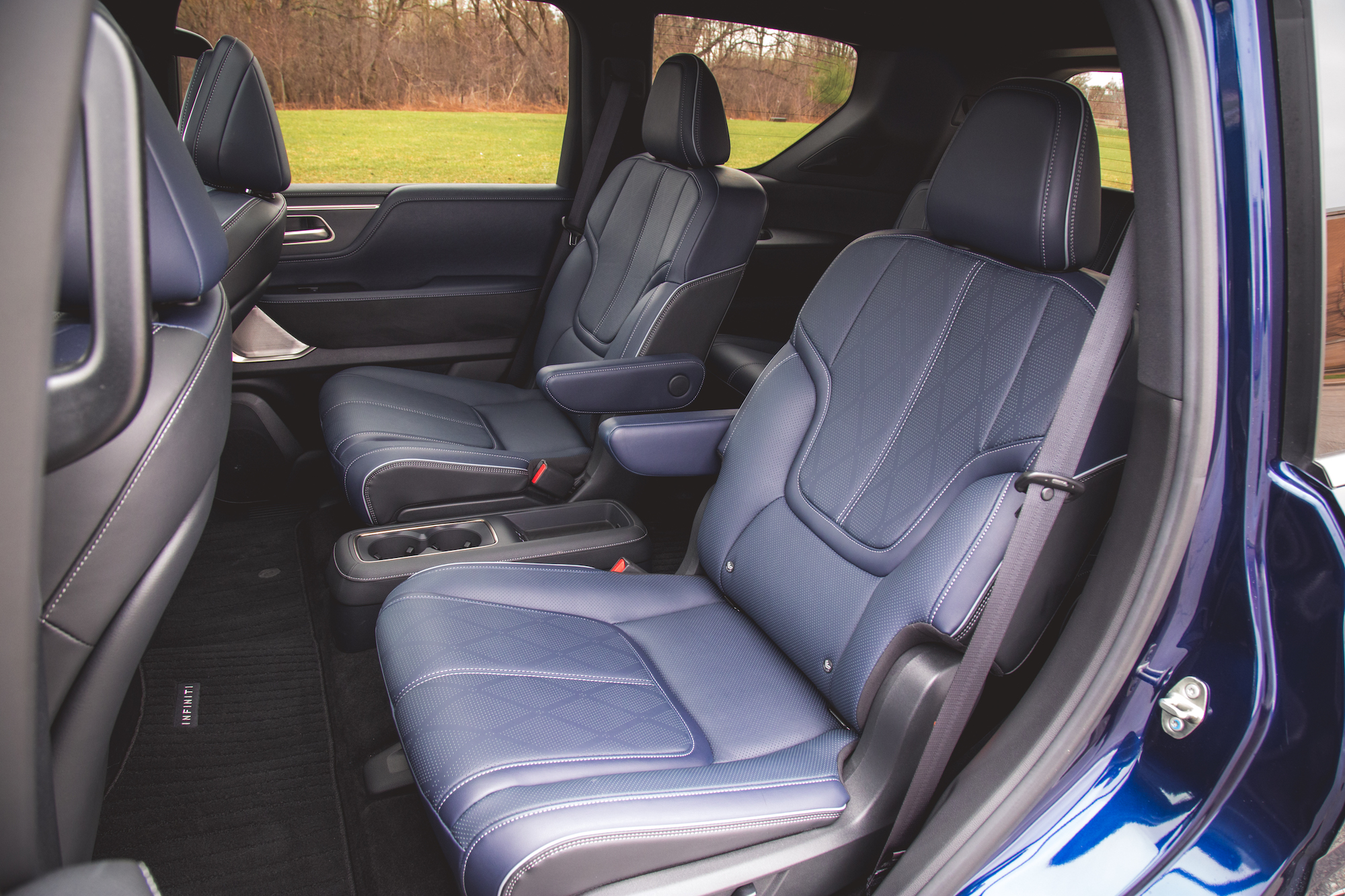 Vista interior de un vehículo moderno que muestra dos asientos delanteros de cuero con tapicería azul y costuras detalladas.