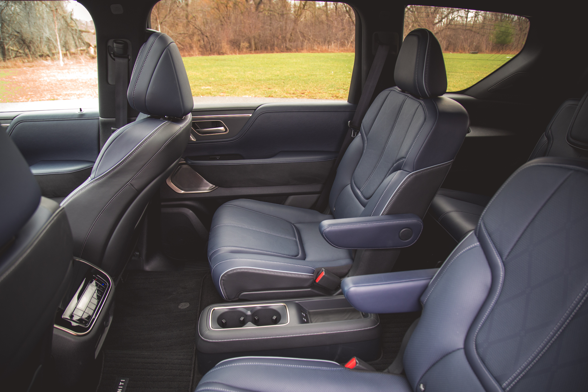 Vista interior de un vehículo que muestra dos cómodos asientos delanteros con tapizado de cuero y apoyabrazos, junto a una consola central con portavasos.