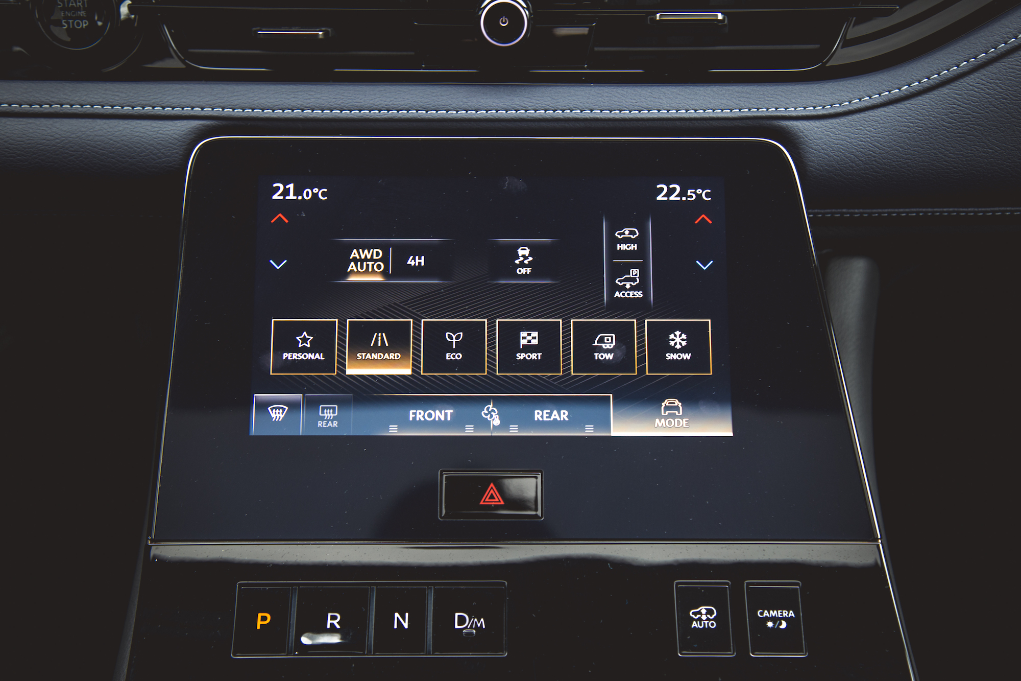 Panel de visualización digital del sistema de información y entretenimiento de un automóvil que muestra la configuración del control del clima, los modos de conducción y las opciones del vehículo.