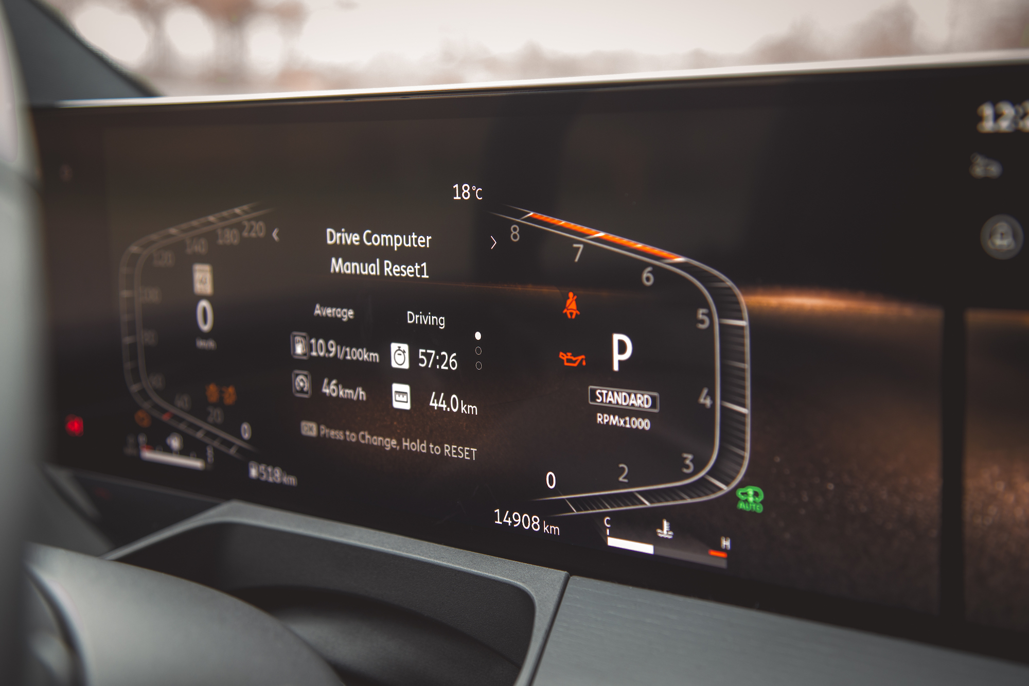 Primer plano de la pantalla de la computadora de manejo digital de un automóvil que muestra estadísticas de manejo, incluido el consumo promedio, el tiempo de manejo, la velocidad, la distancia y las RPM.