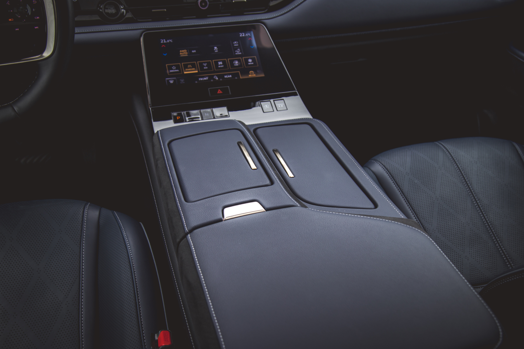 Vista interior de la consola central de un automóvil moderno con pantalla táctil y tapizado de cuero.