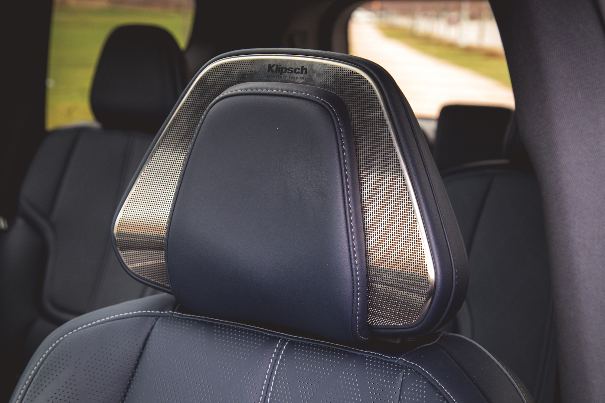 Primer plano del reposacabezas de un automóvil de lujo con integración de altavoz Klipsch y tapicería de cuero de primera calidad.