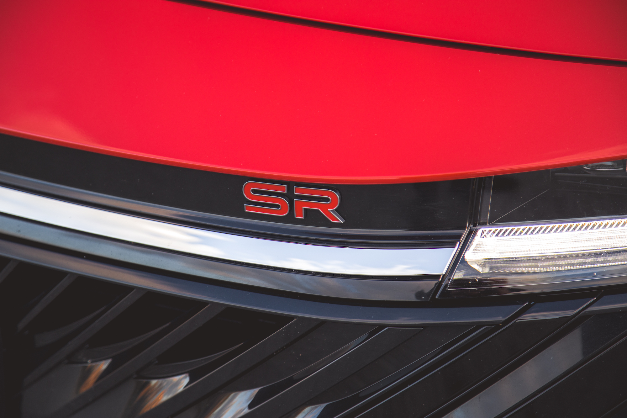 Primer plano del emblema delantero de un automóvil rojo que muestra 