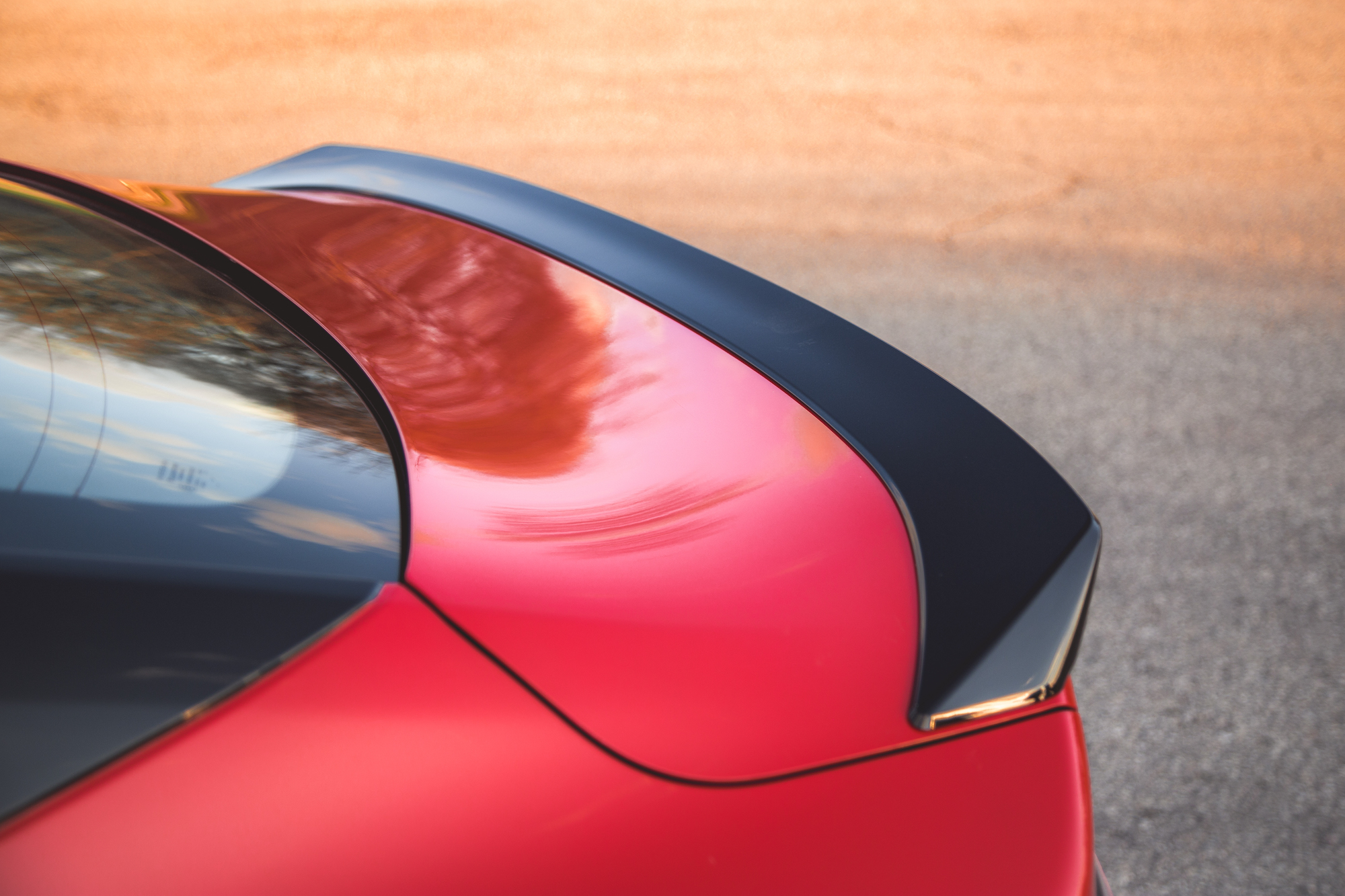 Primer plano del alerón trasero de un coche rojo sobre un fondo borroso.