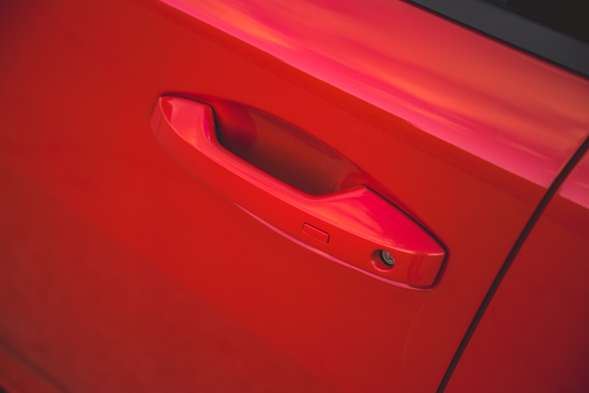 Primer plano de la manija de la puerta de un automóvil rojo.