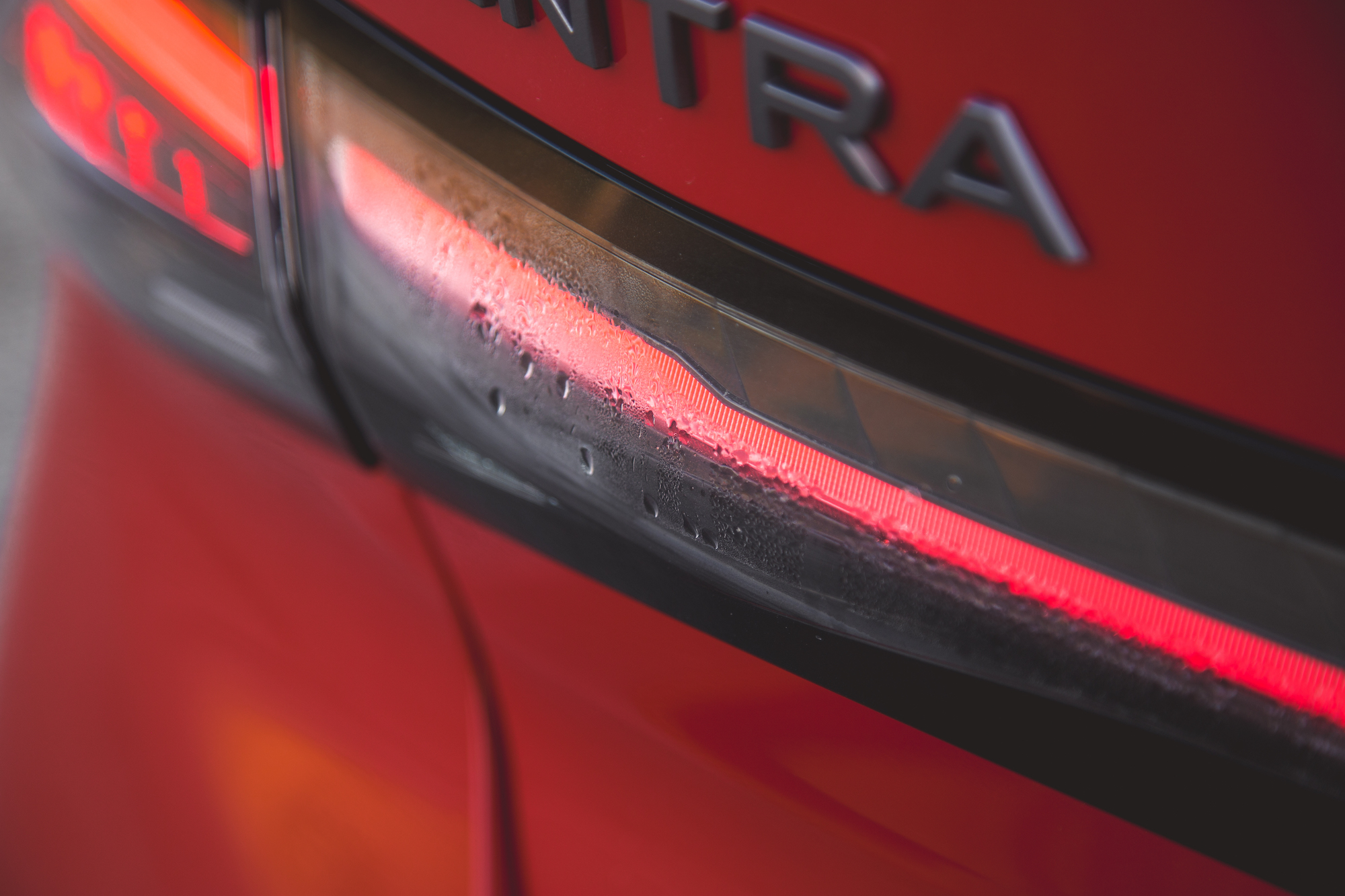 Primer plano de la luz trasera de un automóvil con condensación, con una superficie roja reflectante y la palabra 