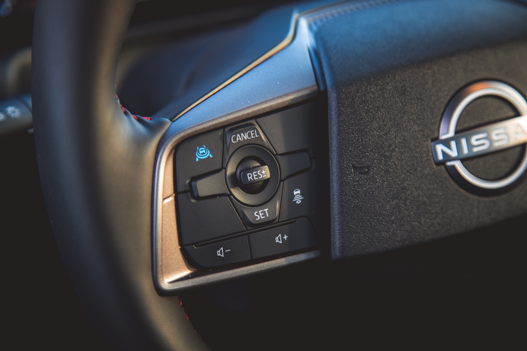 Primer plano de un volante Nissan con botones de control para el control de crucero, incluidos 