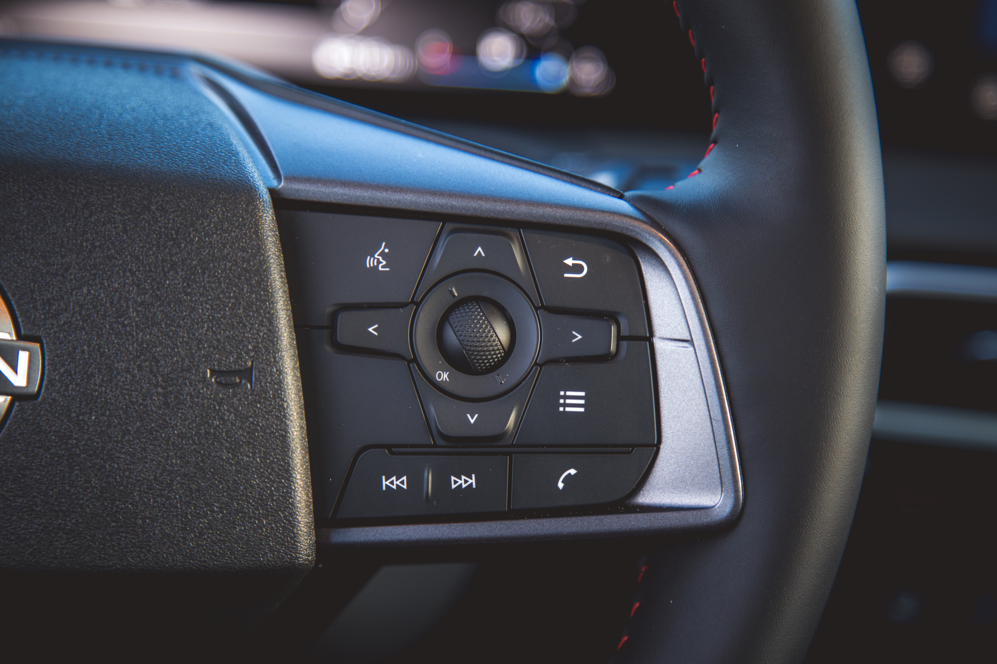 Primer plano del panel de control del volante de un automóvil con botones para control de audio, navegación y funciones del teléfono.