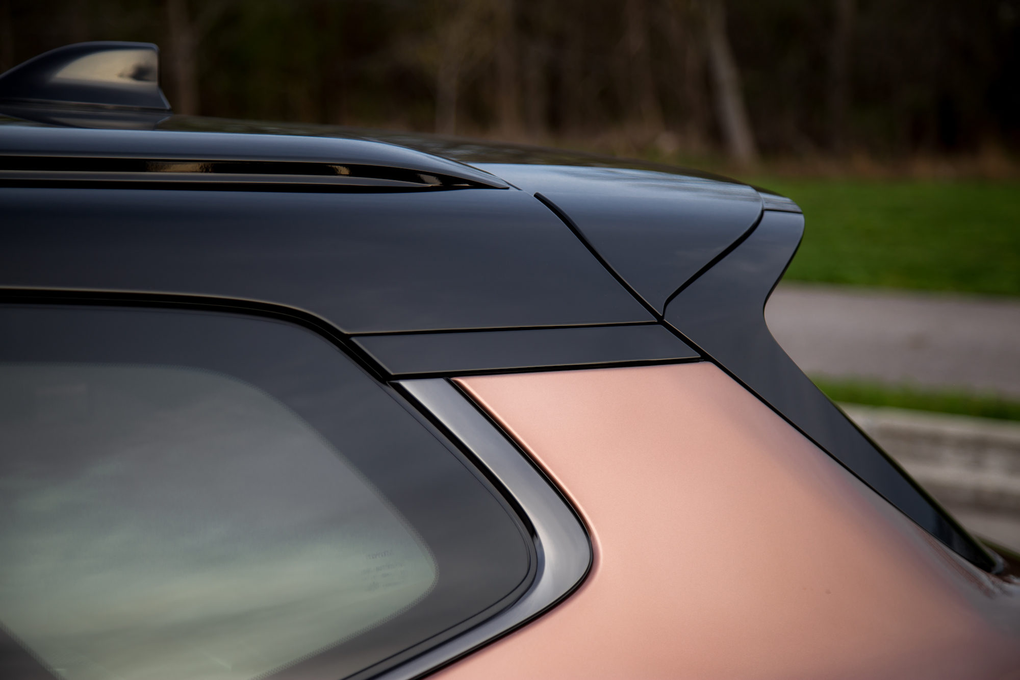 Vista en primer plano de la sección trasera de un automóvil, destacando el elegante diseño de la línea del techo y la transición del acabado negro al color cobre.