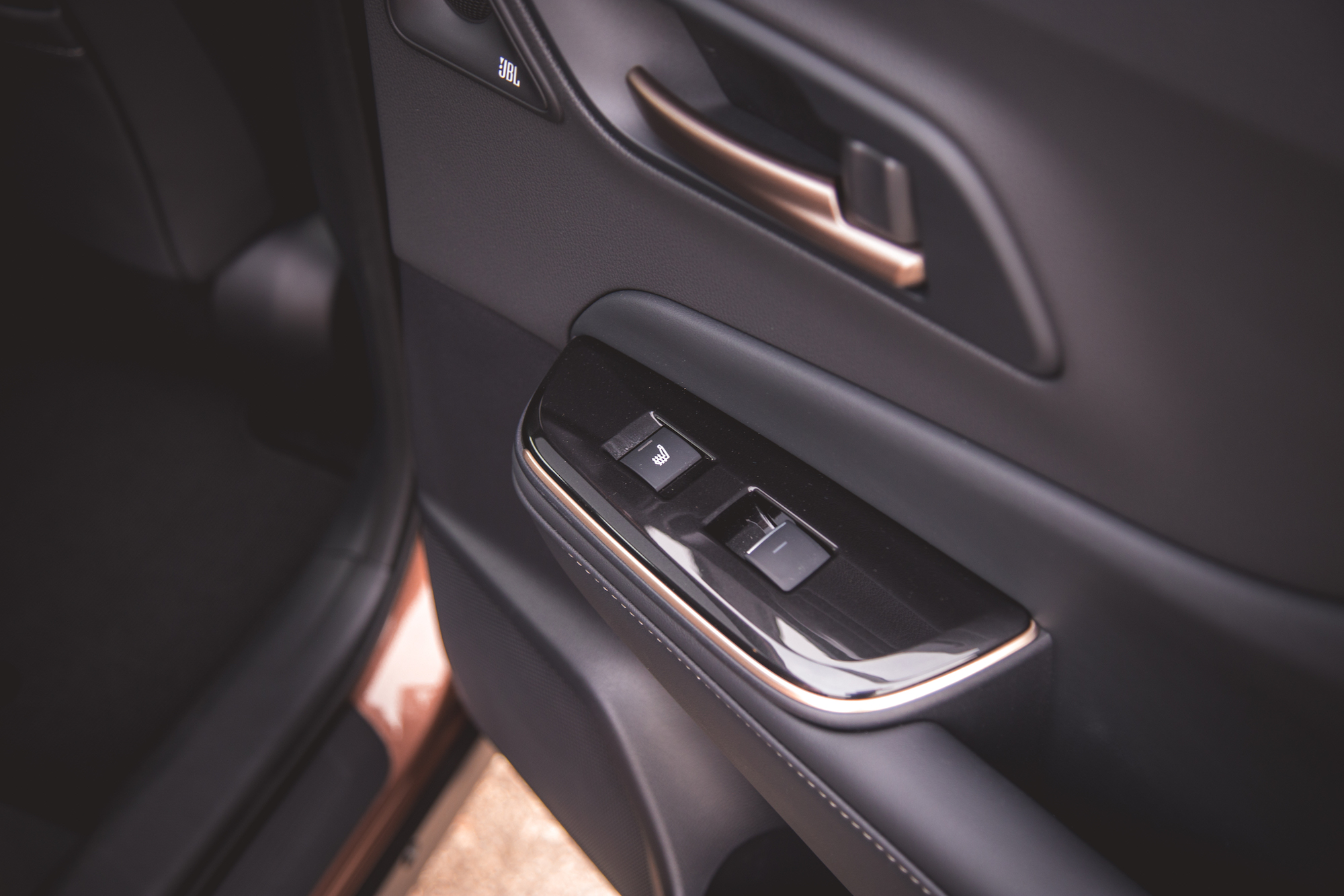 Primer plano del interior de la puerta de un automóvil con botones de control de ventanas y un altavoz.