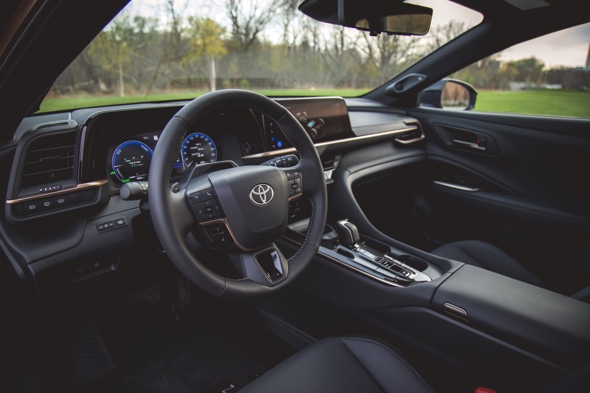 Vista interior de un automóvil Toyota, que presenta un tablero moderno con pantallas digitales, volante con controles y elementos de diseño elegantes.