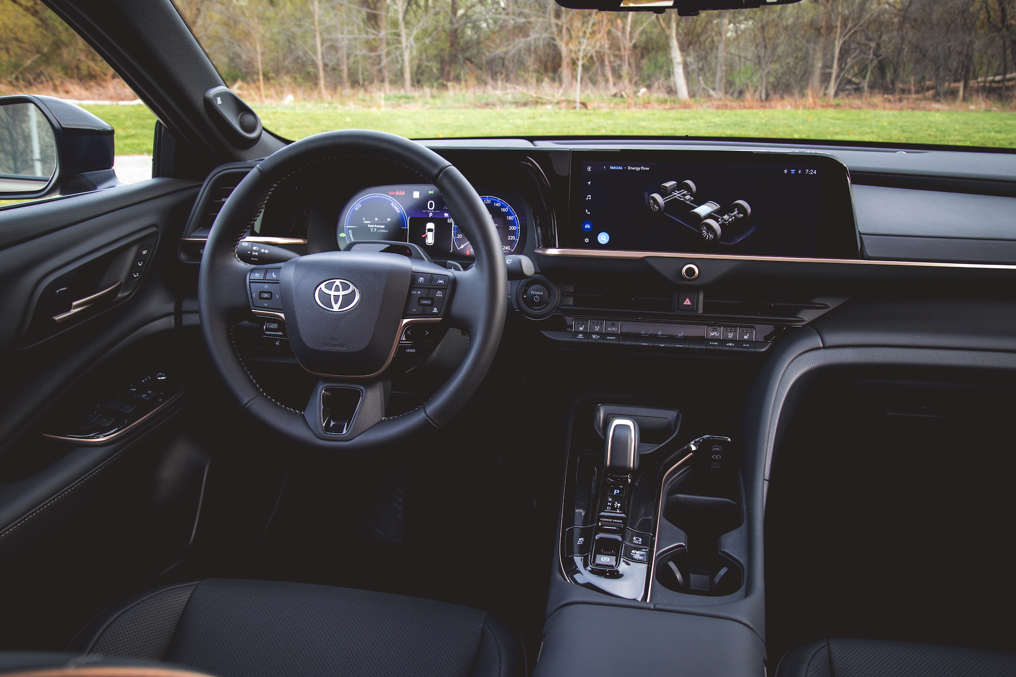 Vista interior de un vehículo Toyota moderno que muestra el volante, la pantalla del tablero y la consola central.